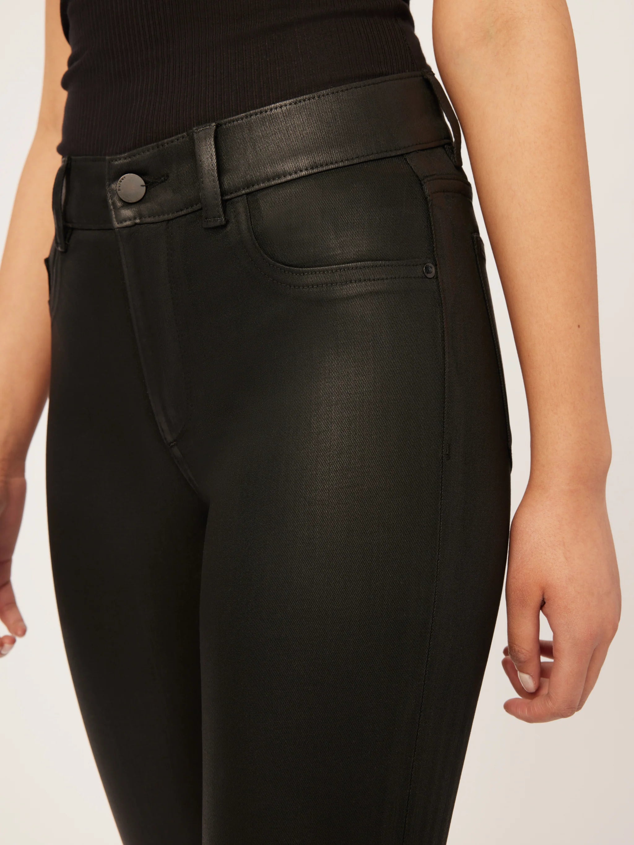 The back view of a woman wearing DL1961 Mara Straight Instasculpt Ankle - Black Coated denim pants.