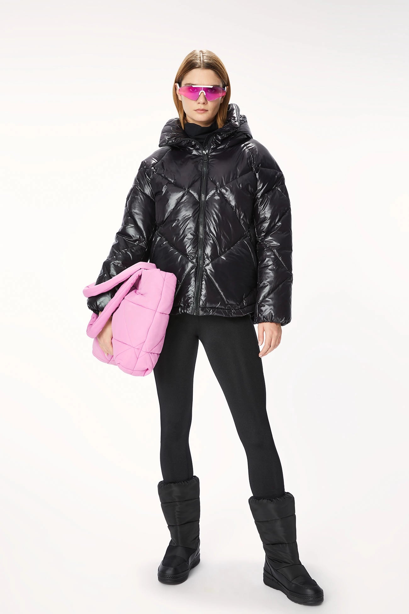 A woman wearing an oversized black OOF puffer jacket with diamond quilting, accessorized with pink sunglasses.