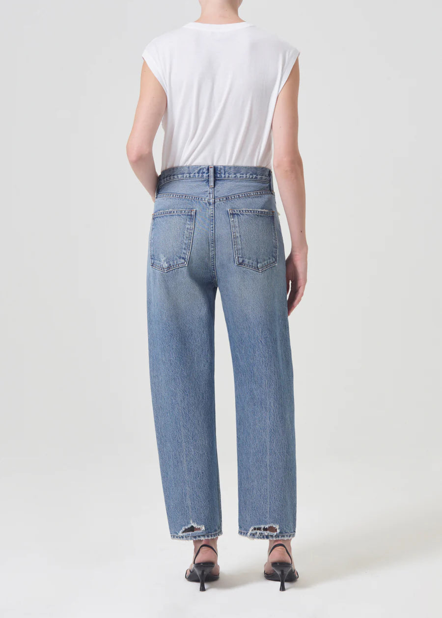 Model wears 90s style straight jeans in light blue. Back view.