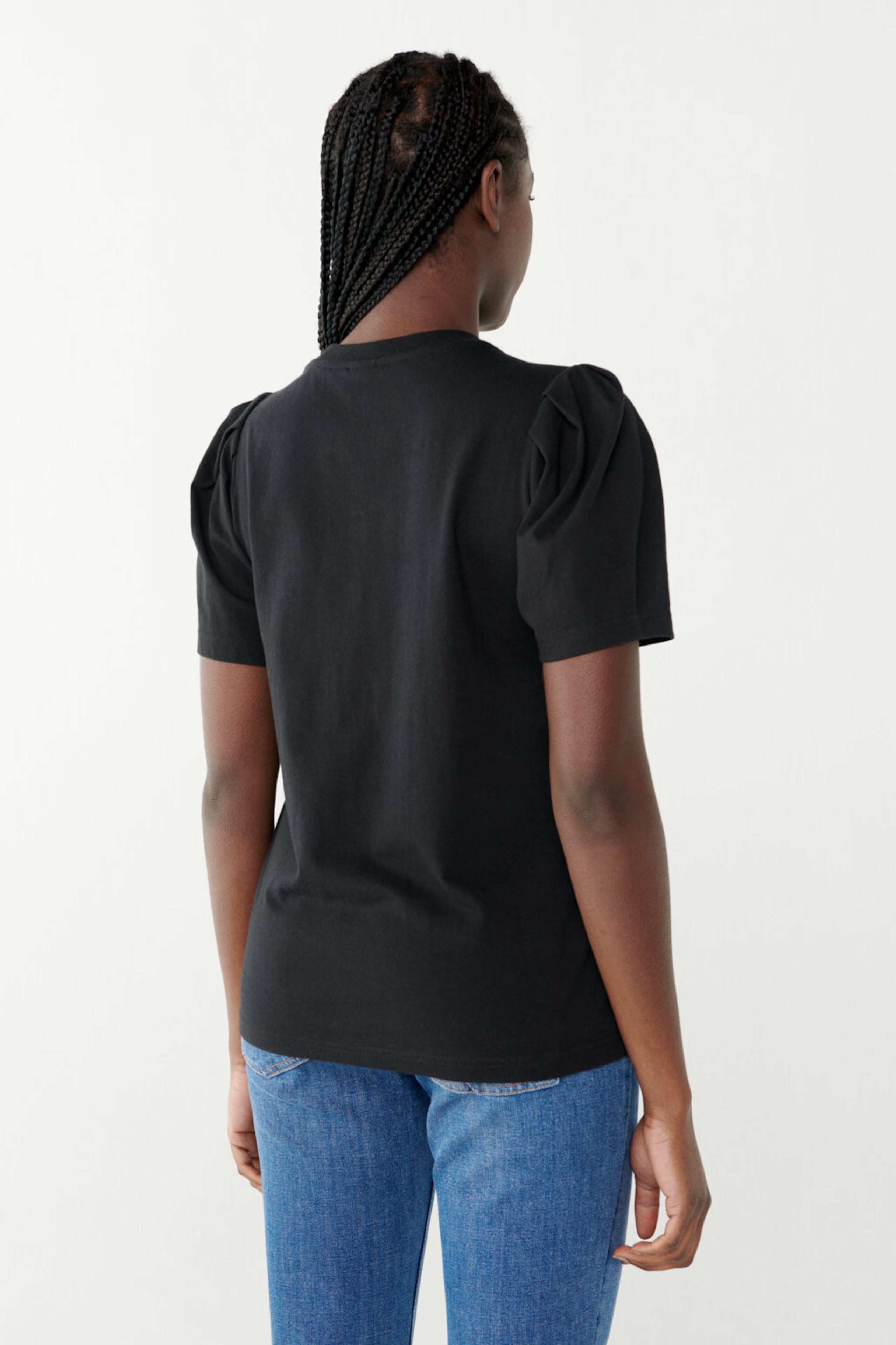 The back view of a woman wearing an Isa Puff Sleeve Tee - Black made from organic cotton by Twist & Tango.