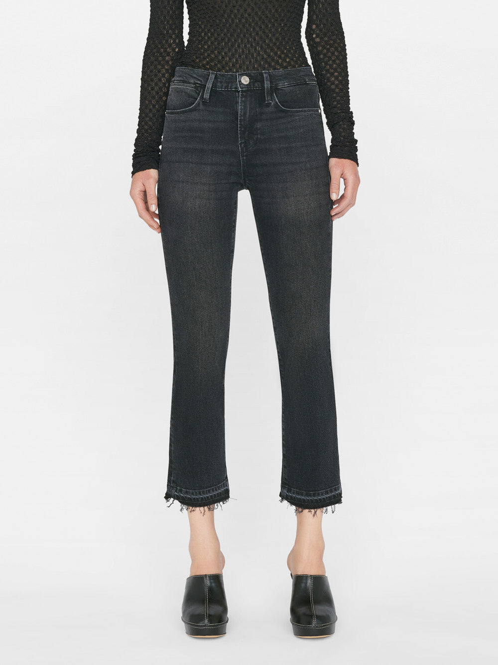 A woman wearing Frame's Le High Straight Released Hem - Hutchison black jeans with frayed hems.