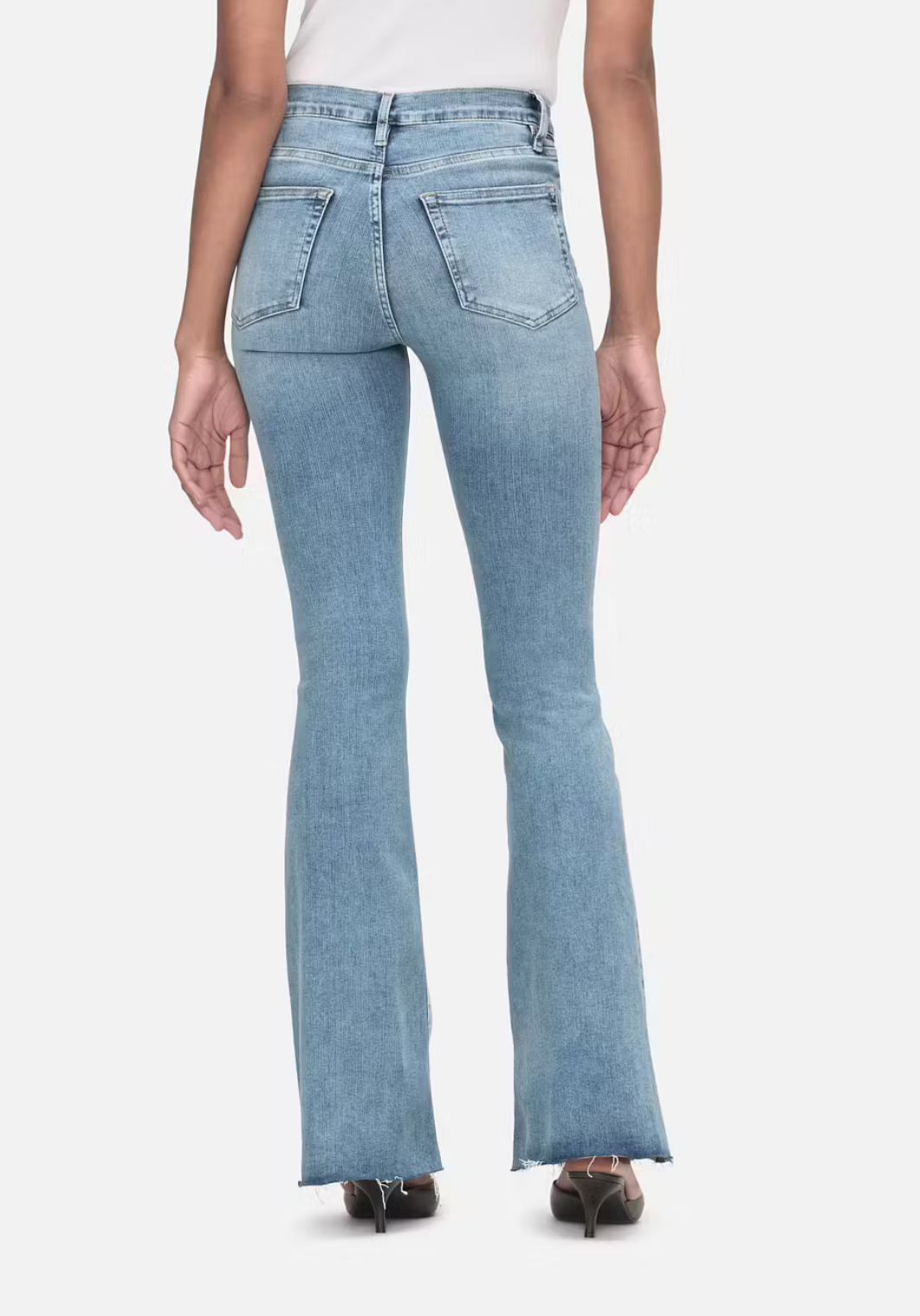 The back view of a woman wearing Frame Le Easy Flare - Colorado high-rise waist flared jeans with a raw hem.