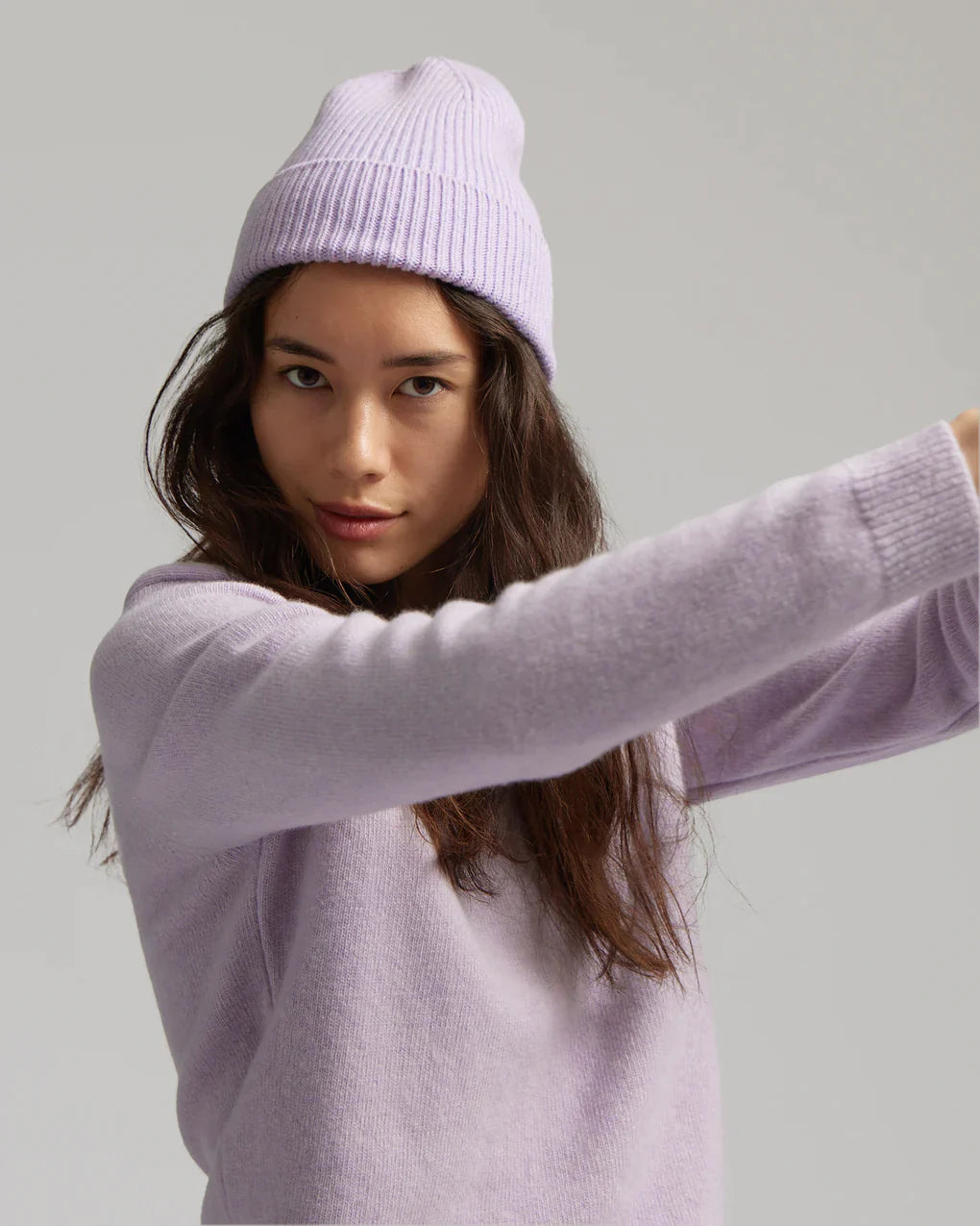 A woman wearing a lavender sweater and beanie.