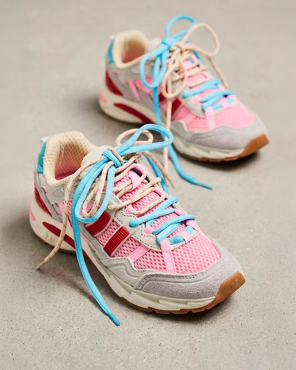A pair of pink, cream, and gray athletic sneakers with blue laces placed on a light gray surface.