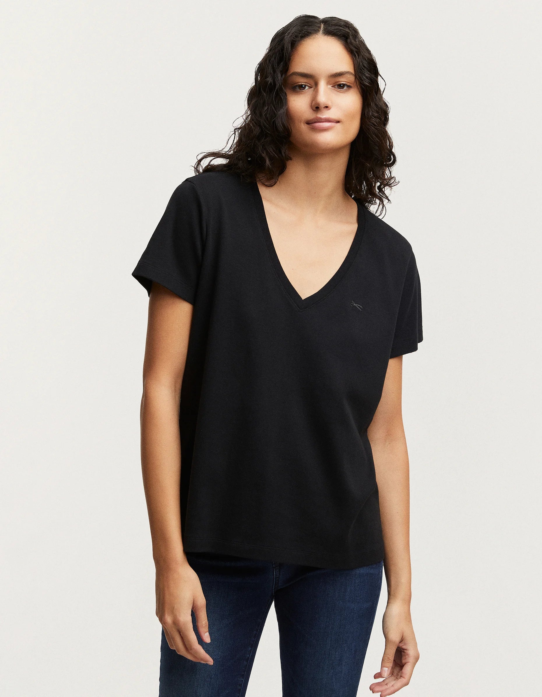 A woman wearing black jeans and a black v-neck t-shirt made of RAMONA Tee Rib Cotton Jersey by Denham.