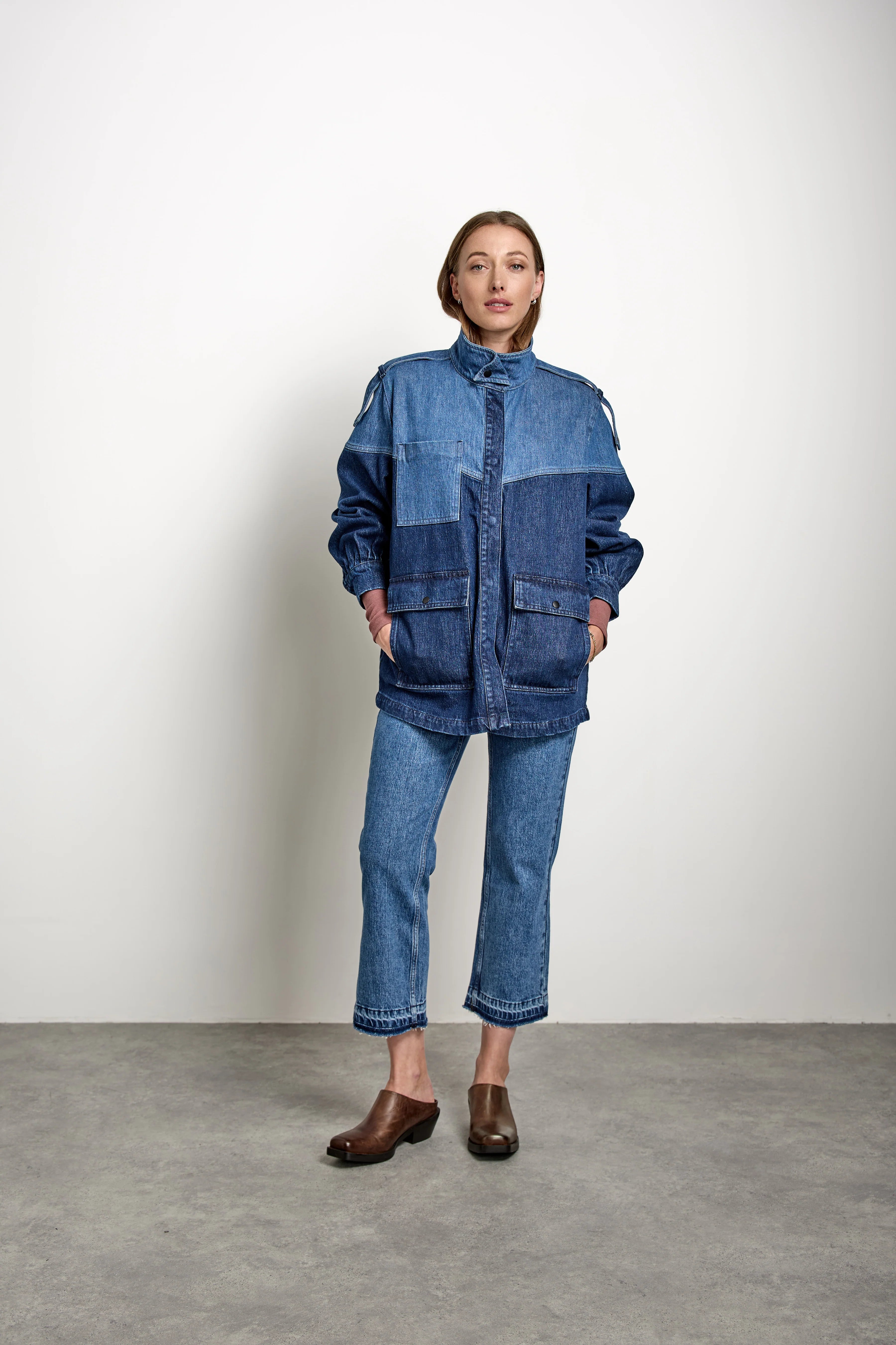 A person stands against a plain background wearing the Seventy & Mochi Bowie Jacket - Americana, paired with blue jeans and brown shoes, hands in the jacket pockets.