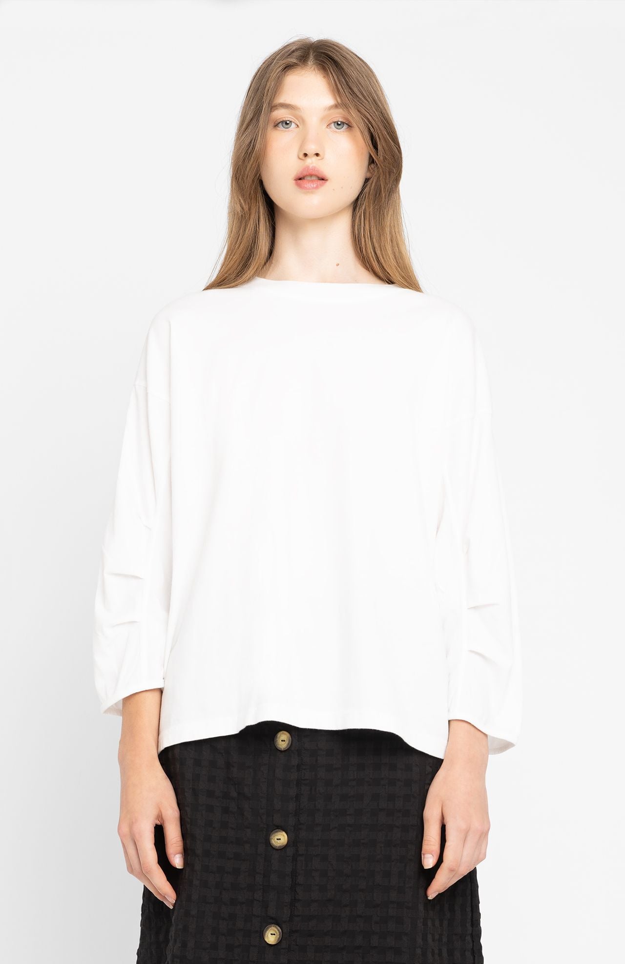 a person wears loreak mendian white structured sleeve t-shirt called Jane with a black skirt on a white background