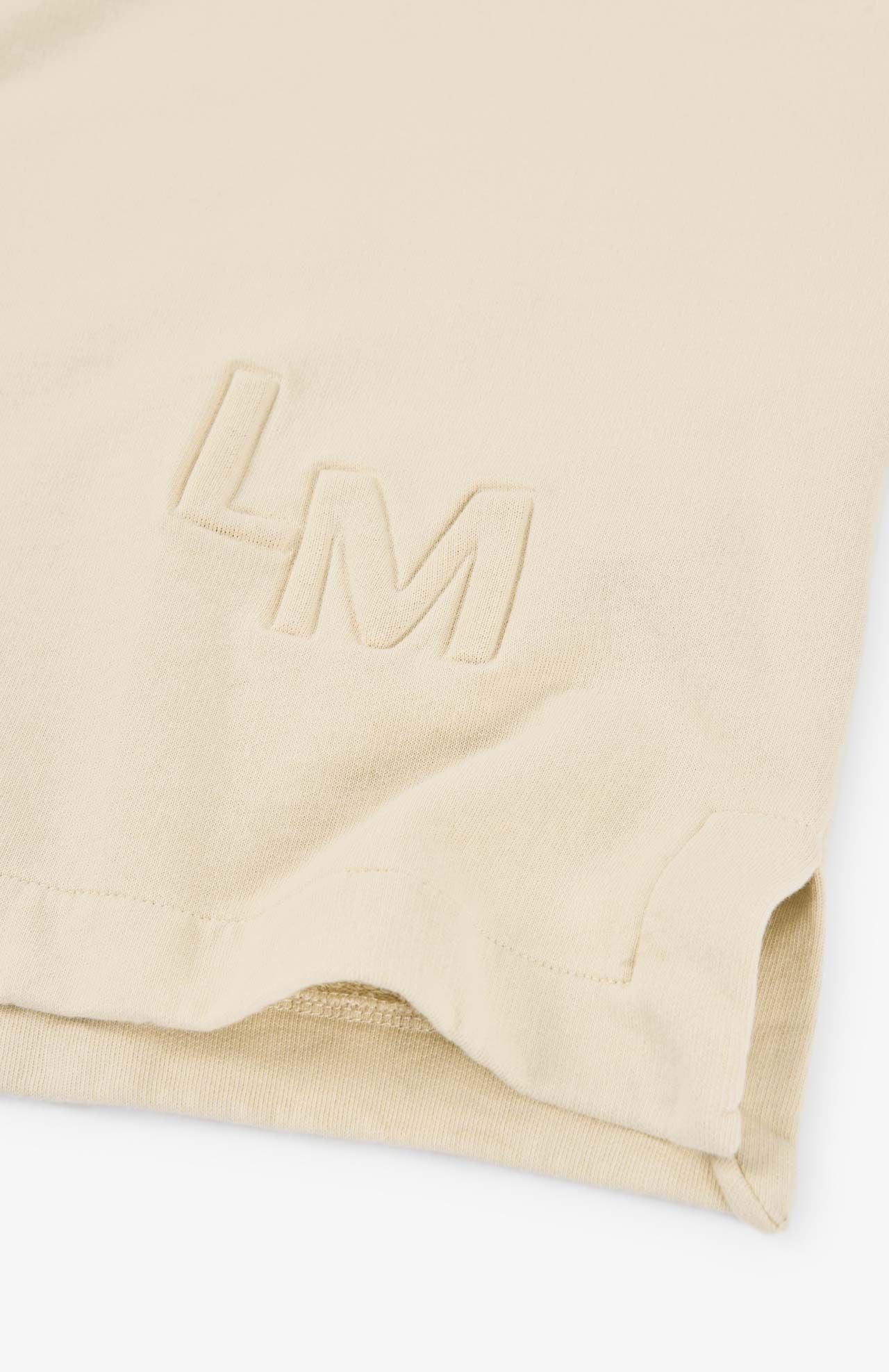 Close-up of the corner of a natural-colored Lise Sweatshirt by Loreak Mendian, featuring the embroidered initials "LM.