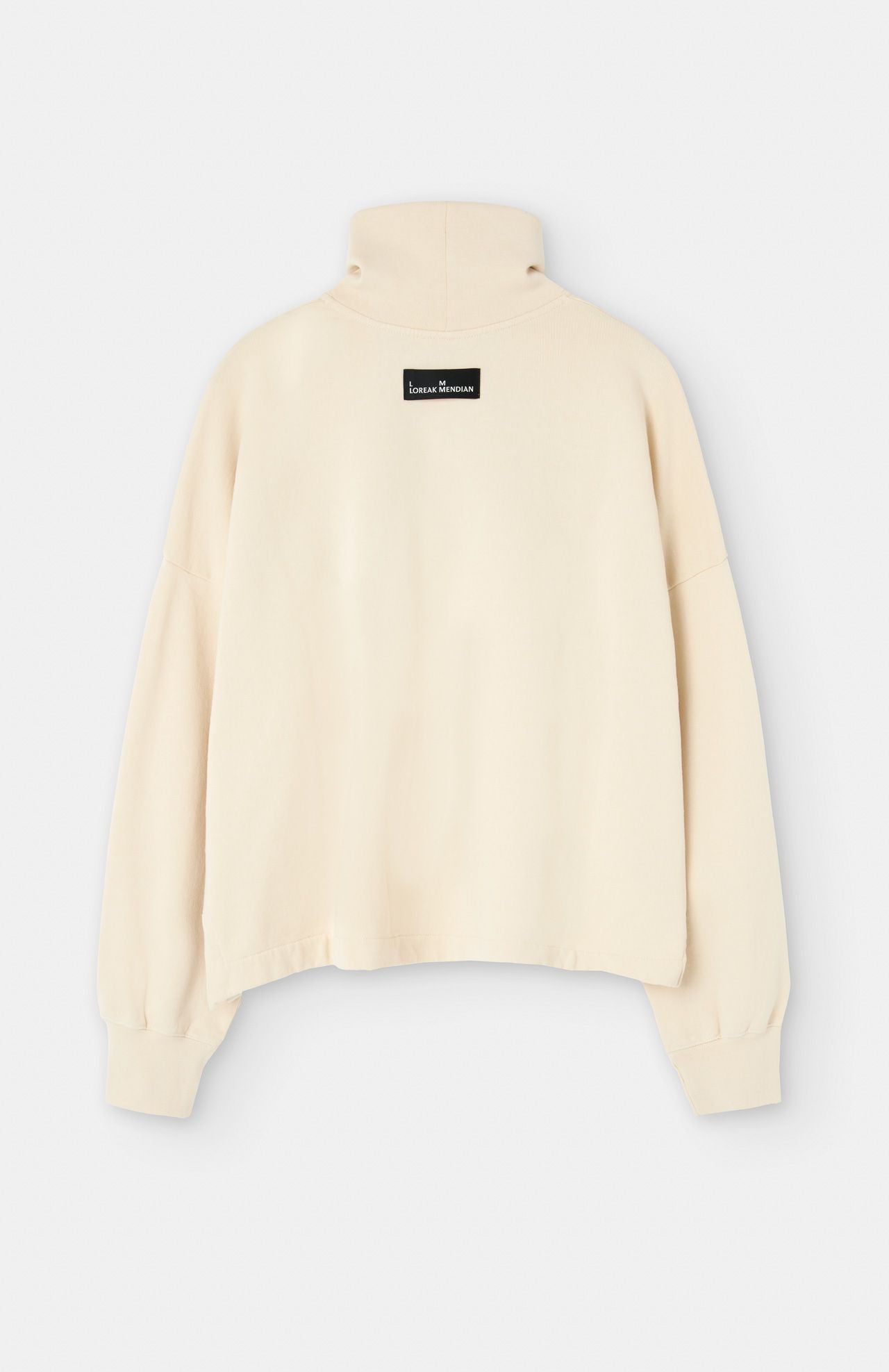 Back view of the Lise Sweatshirt - Natural from Loreak Mendian, featuring a beige long-sleeve, loose fit with a high neck and a rectangular black label on the upper back.