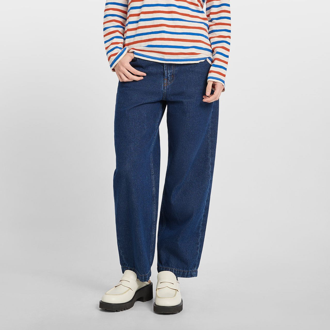 Woman wearing a striped long-sleeve shirt and blue jeans on a white background