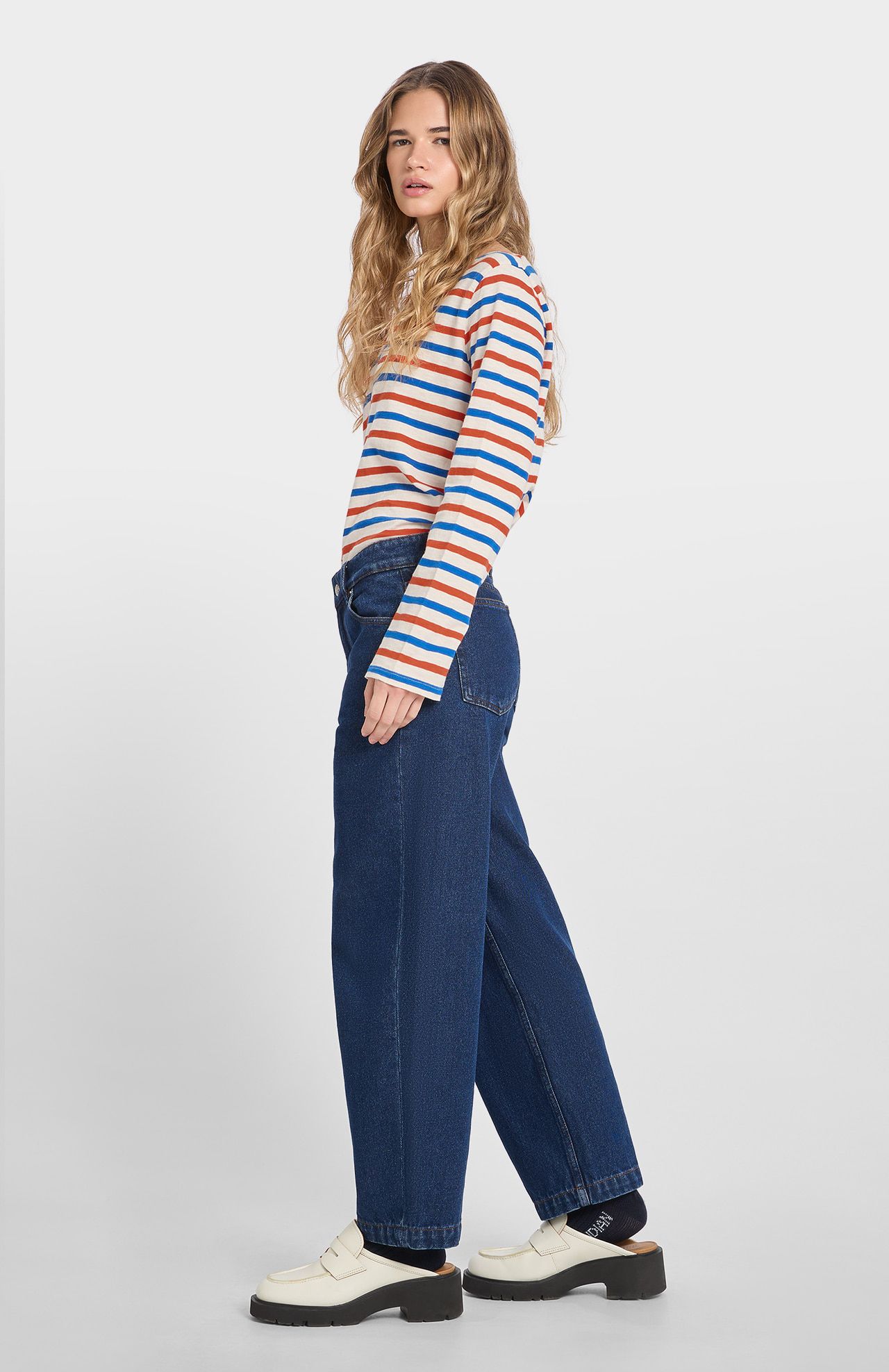 Woman wearing a striped sweater and blue jeans on a white background