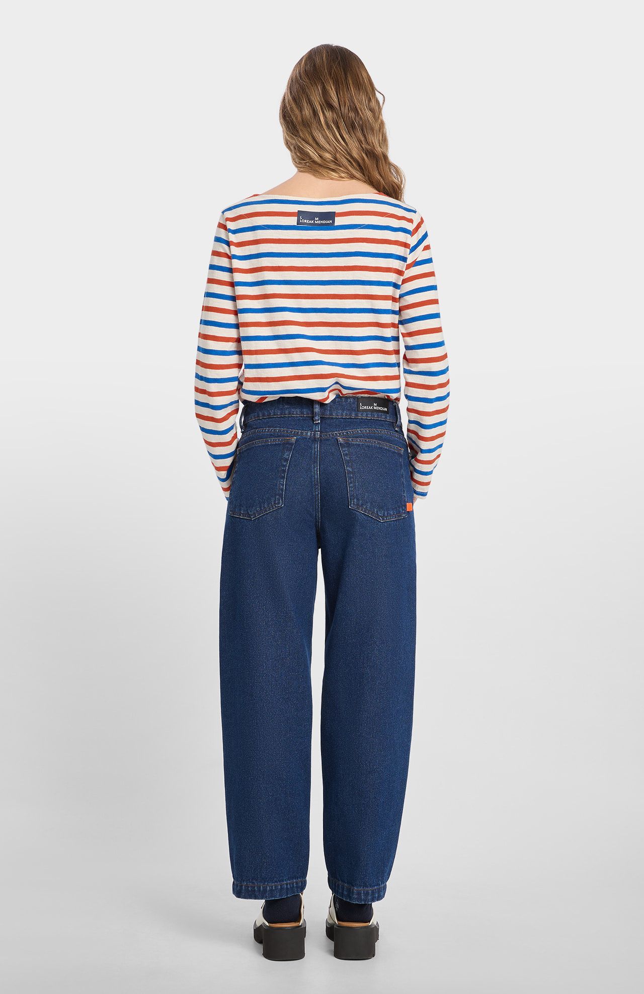 Person wearing a striped shirt and blue jeans on a white background