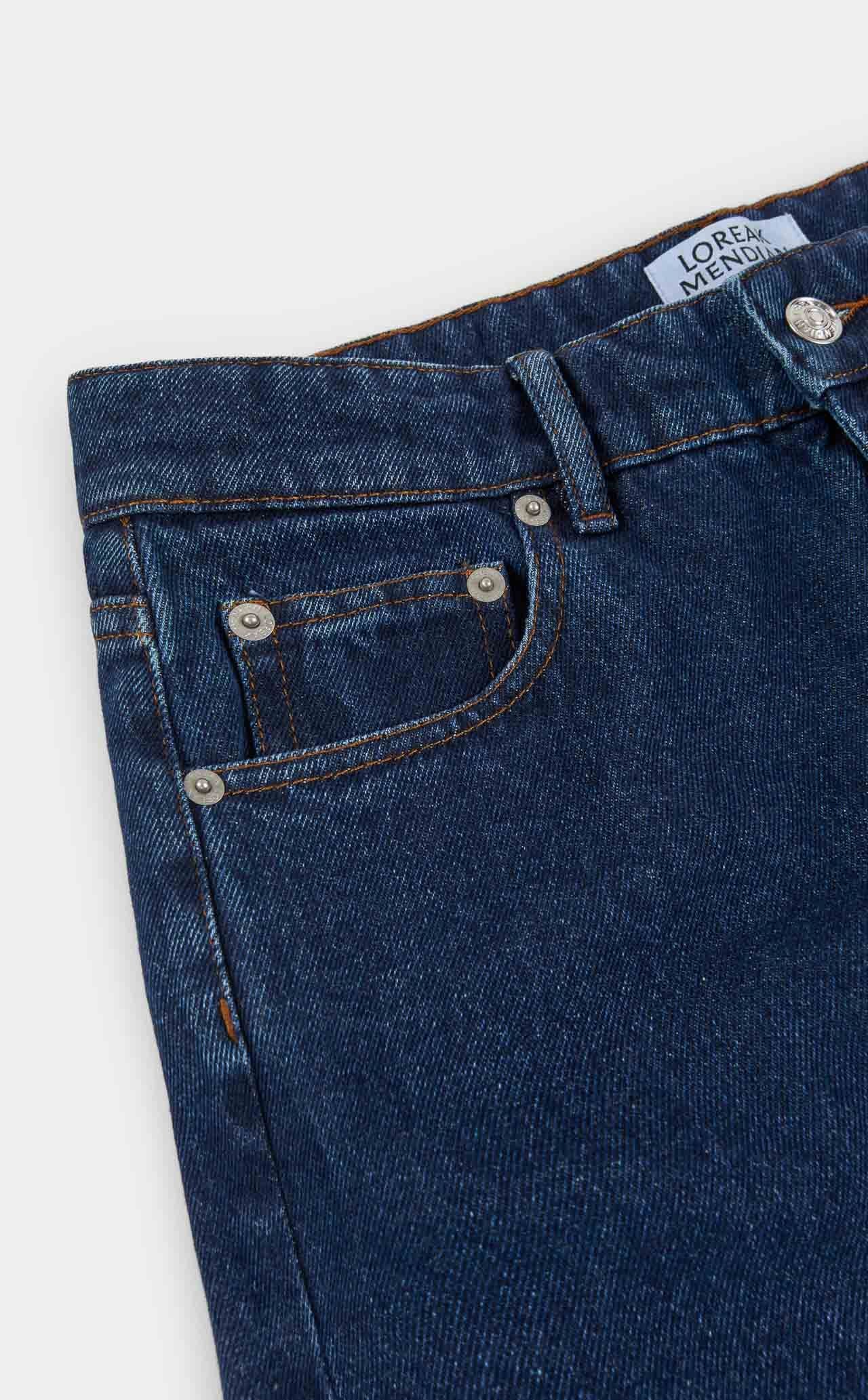 Close-up of blue jeans with a brand label on a white background