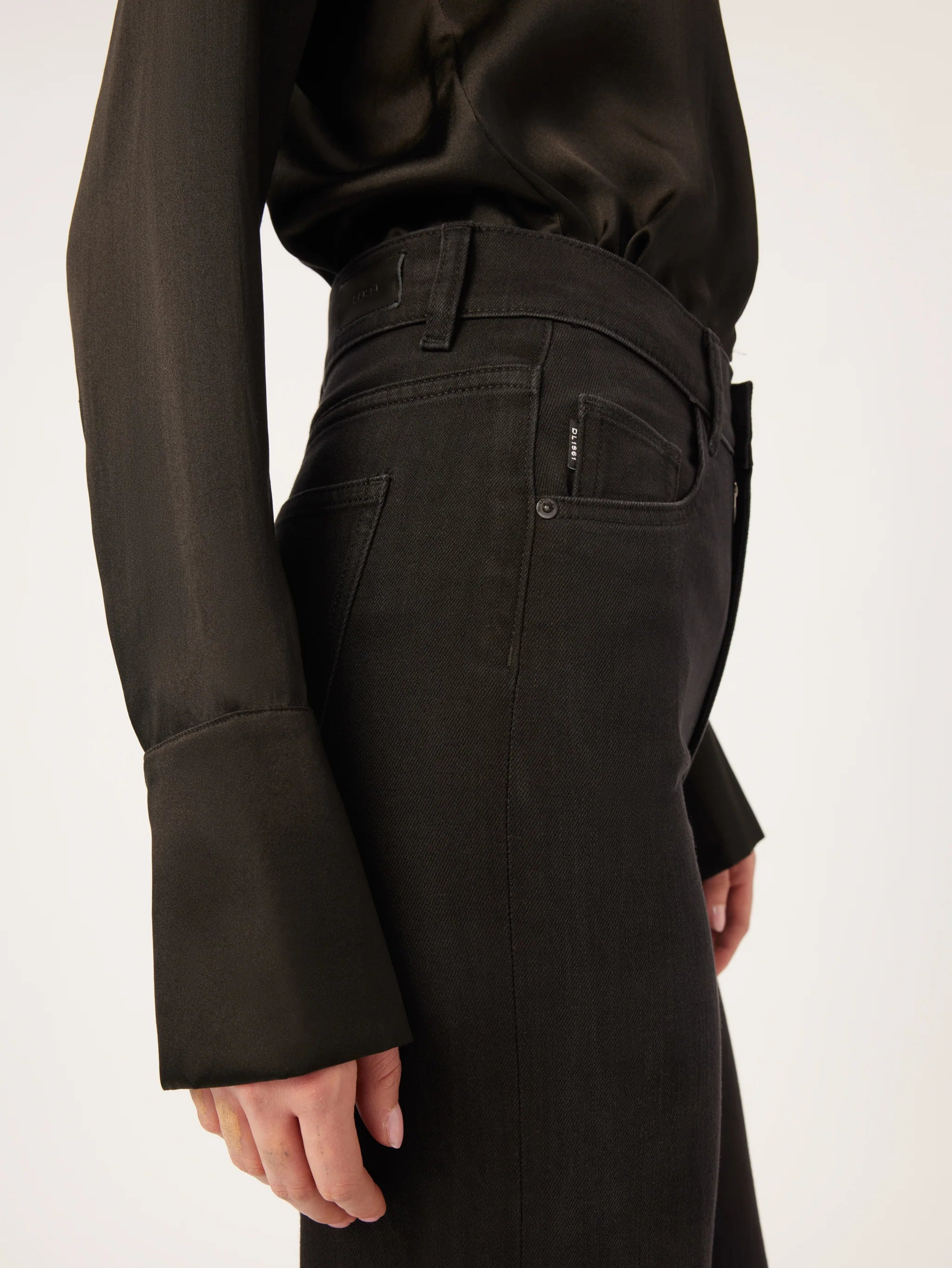 The back view of a woman wearing DL1961 Hepburn Wide Leg - Jet Black vintage high-rise jeans.