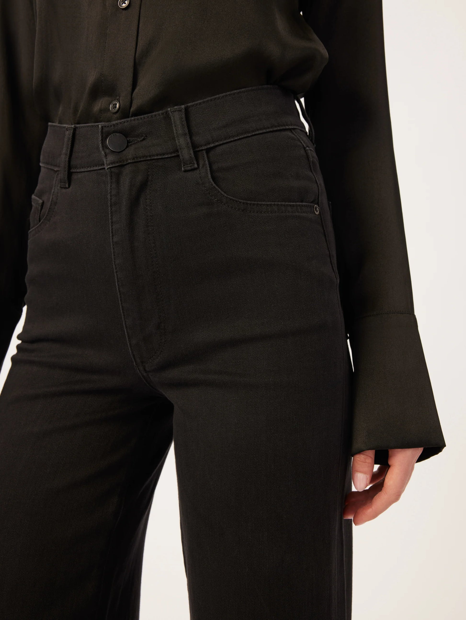 A woman wearing DL1961 Hepburn Wide Leg - Jet Black jeans with a vintage high-rise and a black blouse.