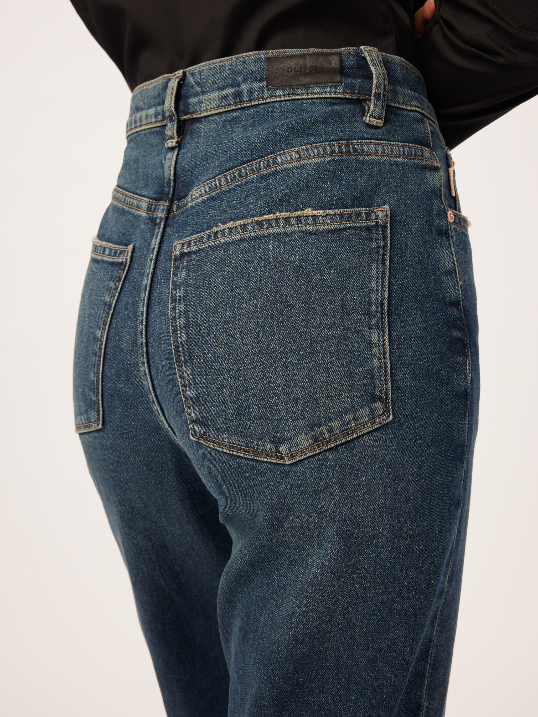 The back view of a woman wearing DL1961 Enora Cigarette High Rise - Broadbay jeans with an ultra high-rise waist.