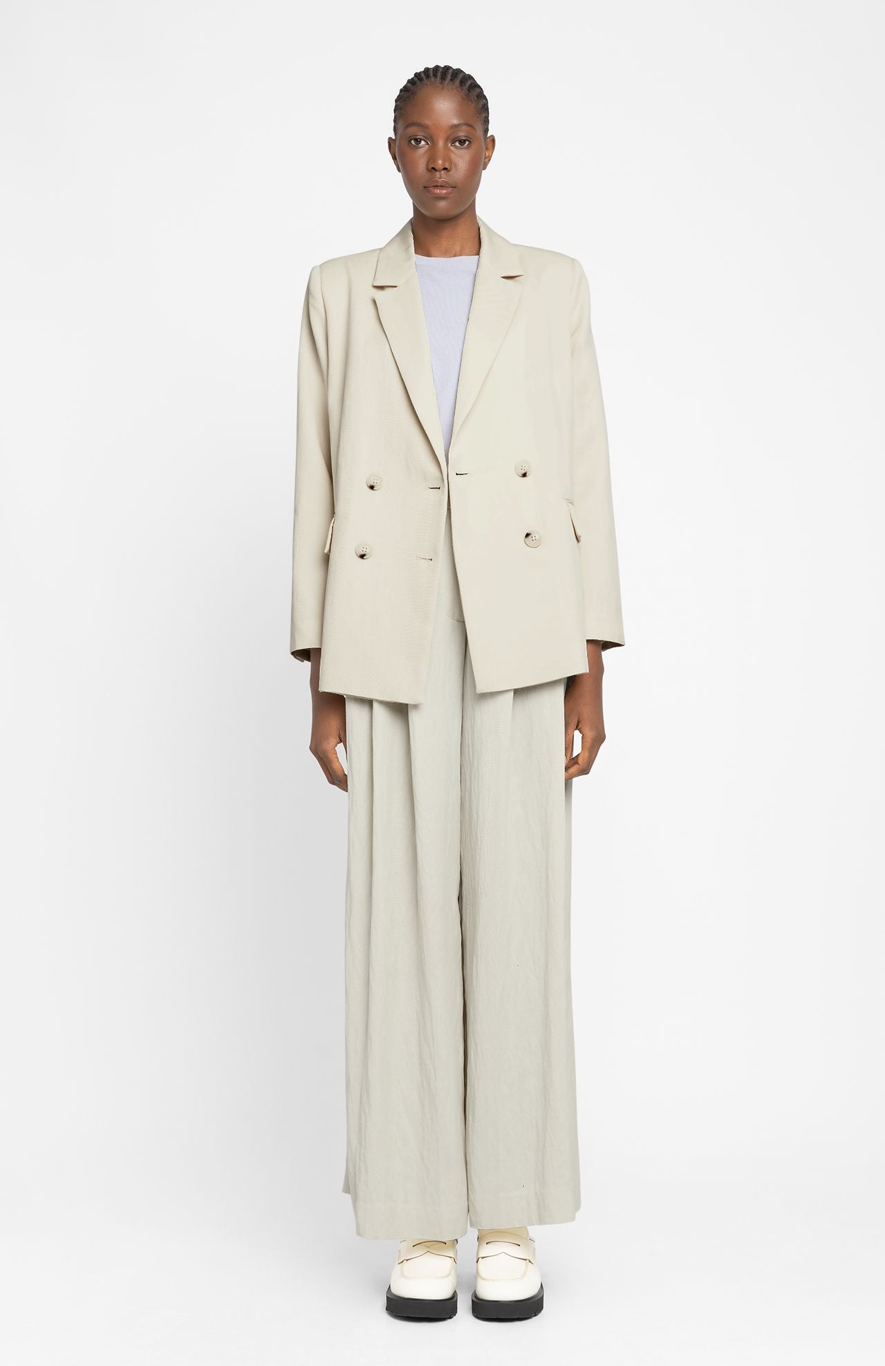 model wears loreak mendian suarbe tailored jacket blazer with matching trousers in cream and white shoes