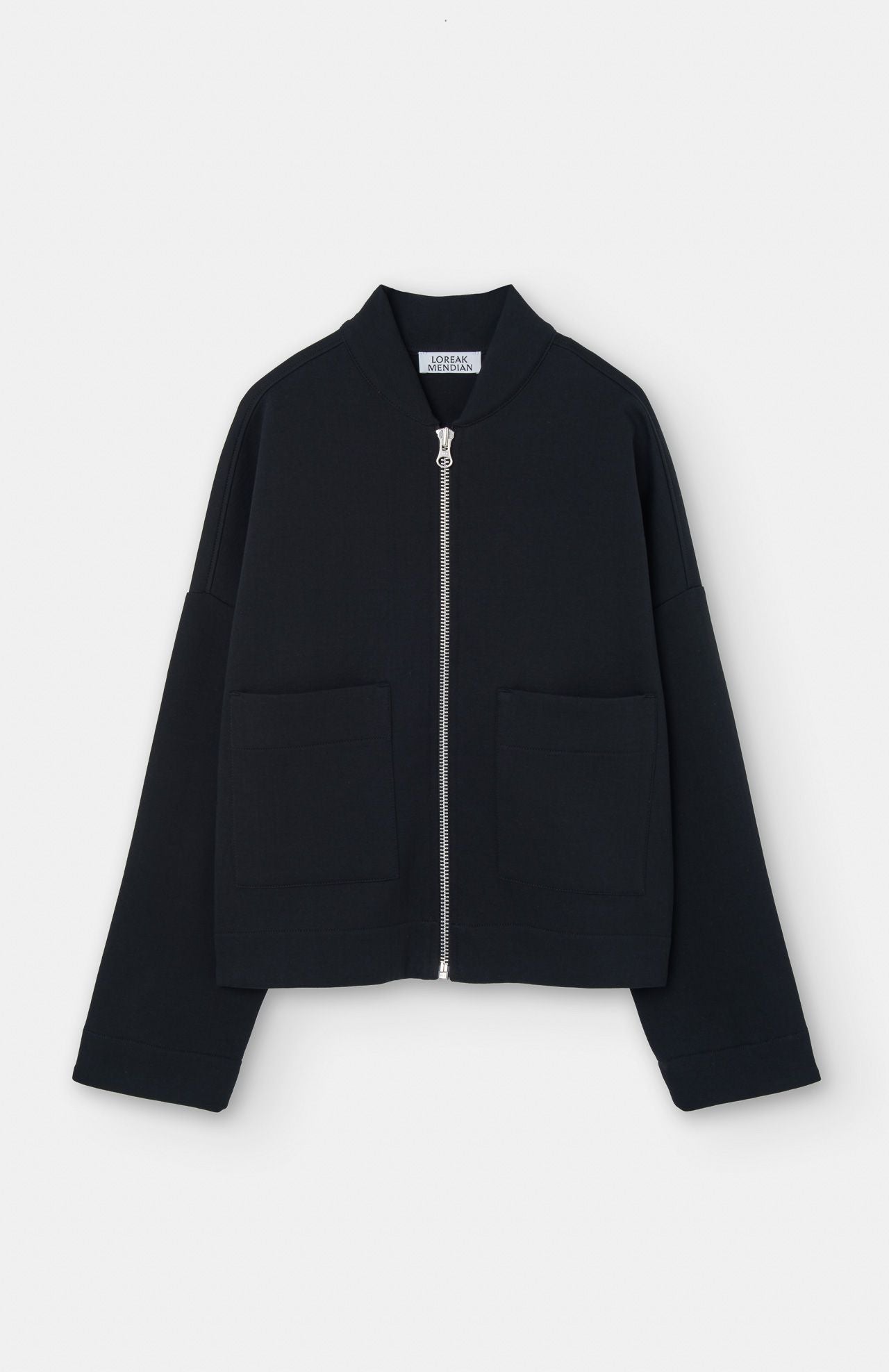The Lili Cropped Jacket by Loreak Mendian is a black, long-sleeve, collarless jacket with two front pockets, shown against a plain white background.