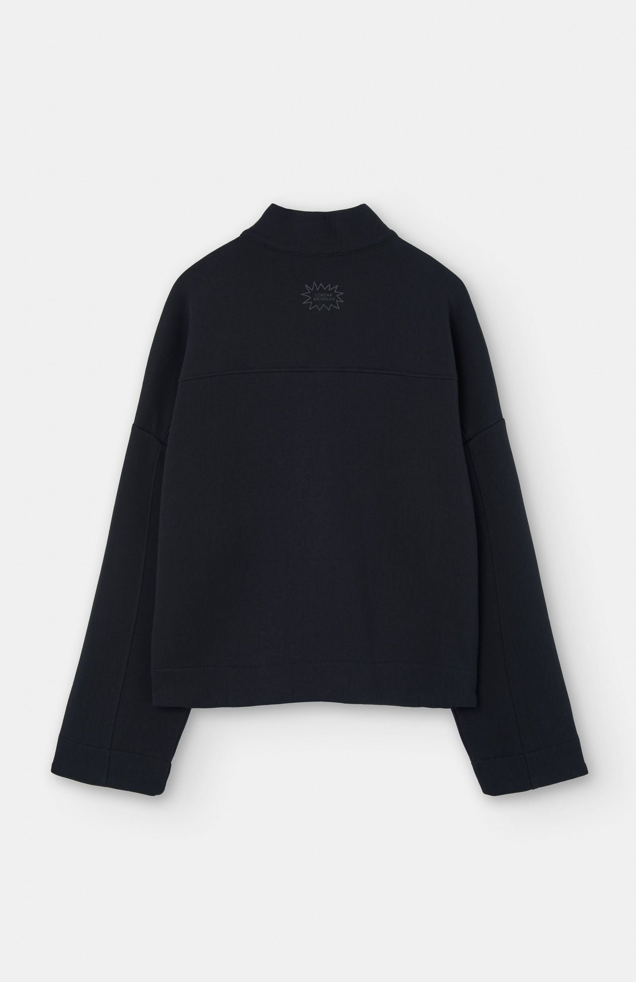 The Loreak Mendian Lili Cropped Jacket in black is shown from the back, featuring a small embroidered sunburst below the collar.