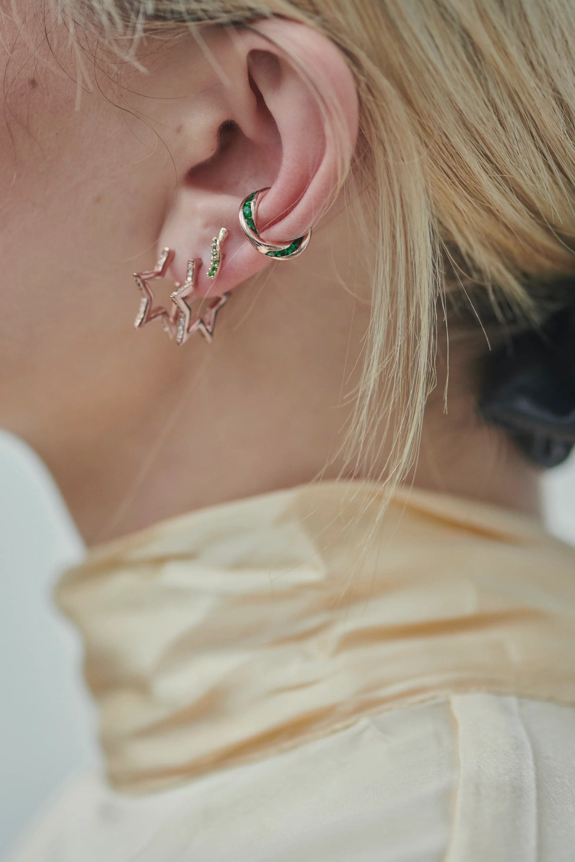 A woman is wearing a pair of Treasure Cuff - Rose Gold ear cuffs with stars on them, no piercing required from Tada & Toy.