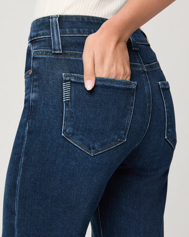 Close-up of a person wearing Paige Leenah Slim Wide Leg jeans in the deep Basilica wash, with one hand partially tucked into the back pocket.