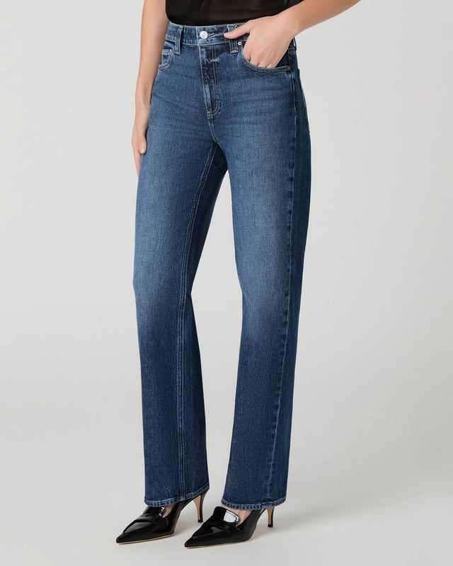 Wearing the Paige Stevie High Rise Straight Leg jeans in Jetty, styled with black pointed-toe heels and set against a clean, light background—an ensemble that reflects timeless, heritage-inspired denim style.