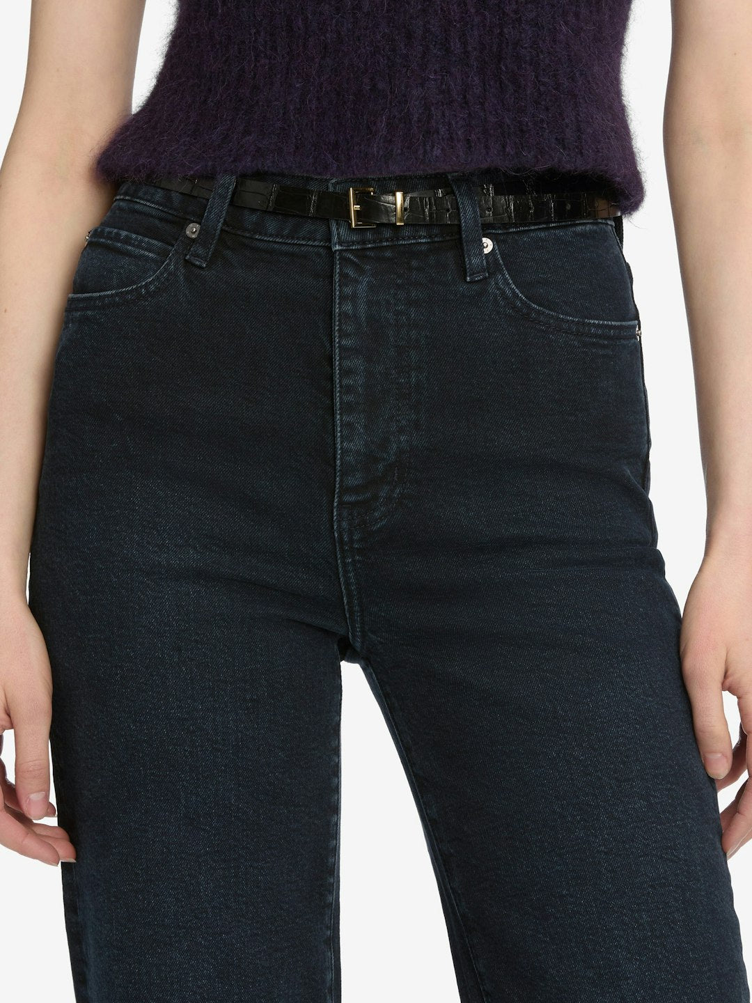 A person wearing Frame The Wide - Untold ultra high-rise indigo jeans by Frame, paired with a black belt and a dark purple sleeveless top.