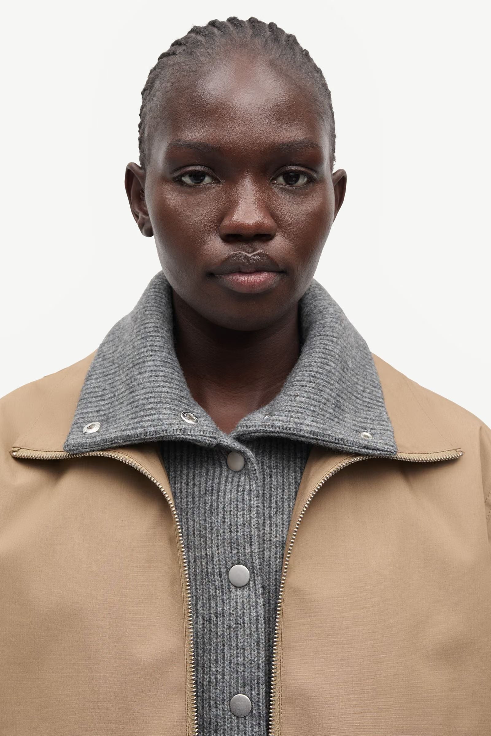 A person with short hair wears the lead grey Sabianco Jacket by Samsøe Samsøe over a gray ribbed button-up sweater, facing forward against a plain white background.