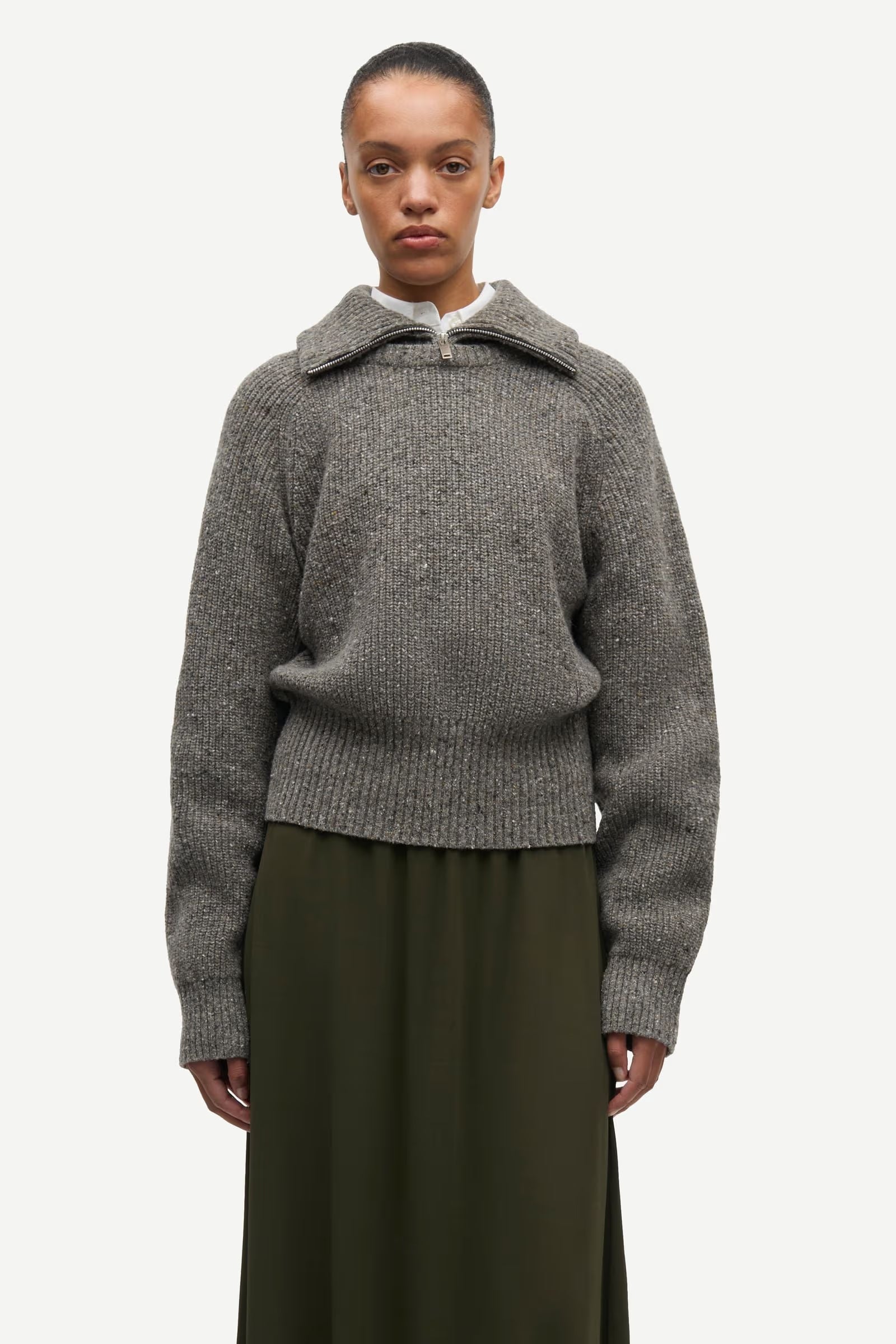 A person wearing the Samsøe Samsøe Saamandy Turtleneck in Lead Grey Melange and a dark green skirt, standing against a plain white background.
