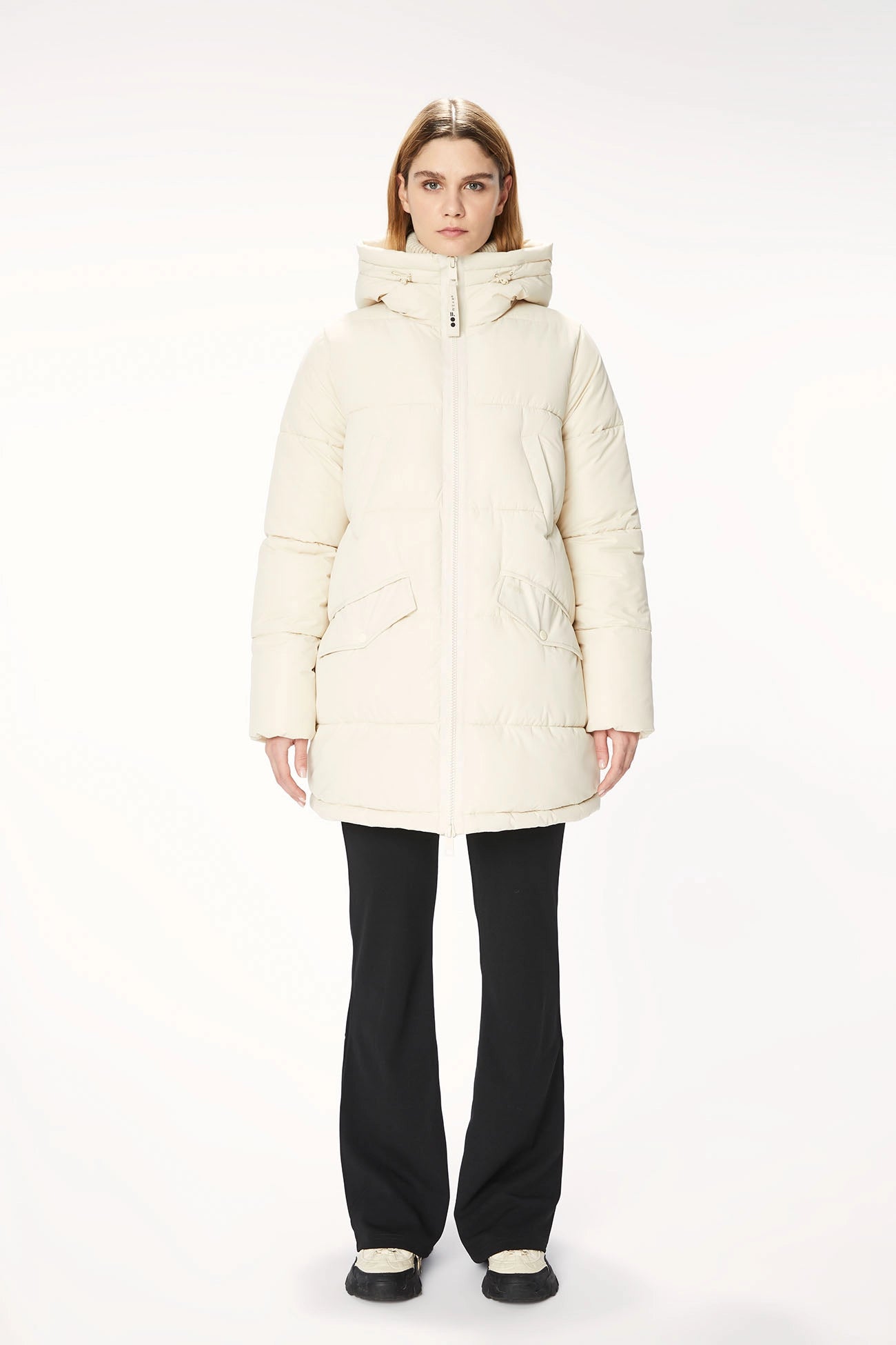 A woman, wearing an OOF Jacket 9098 - Water-Resistant Nylon - Cream, featuring an adjustable drawstring bottom hem for a generous fit.