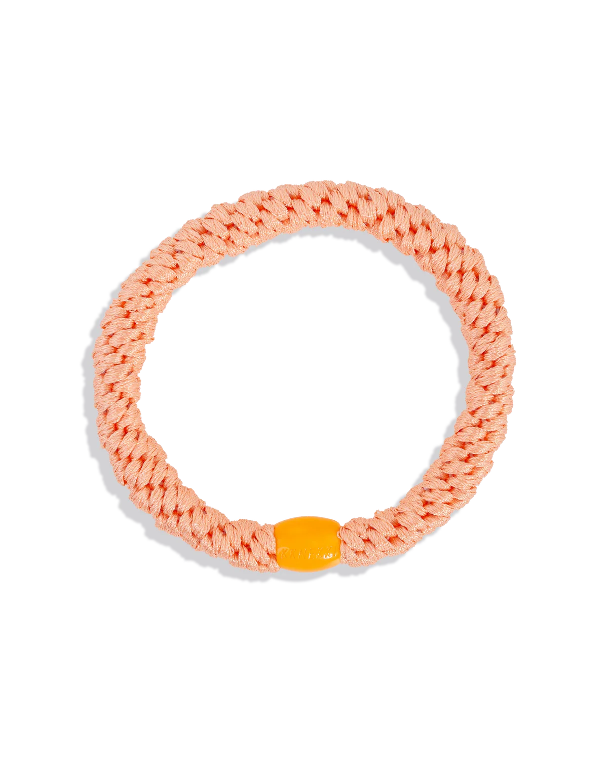 Shown against a white background, the KKNEKKI Hair Tie - Original is peach-colored with a braided elastic design and yellow plastic clasp, offering a gentle yet secure hold for comfortable all-day wear.
