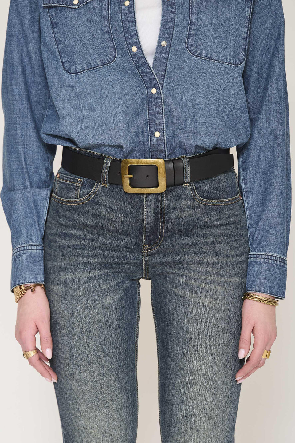 Model wears the MKTStudio Douce Belt in Black, styled with a blue denim shirt and blue jeans; image shown from shoulders to mid-thigh.