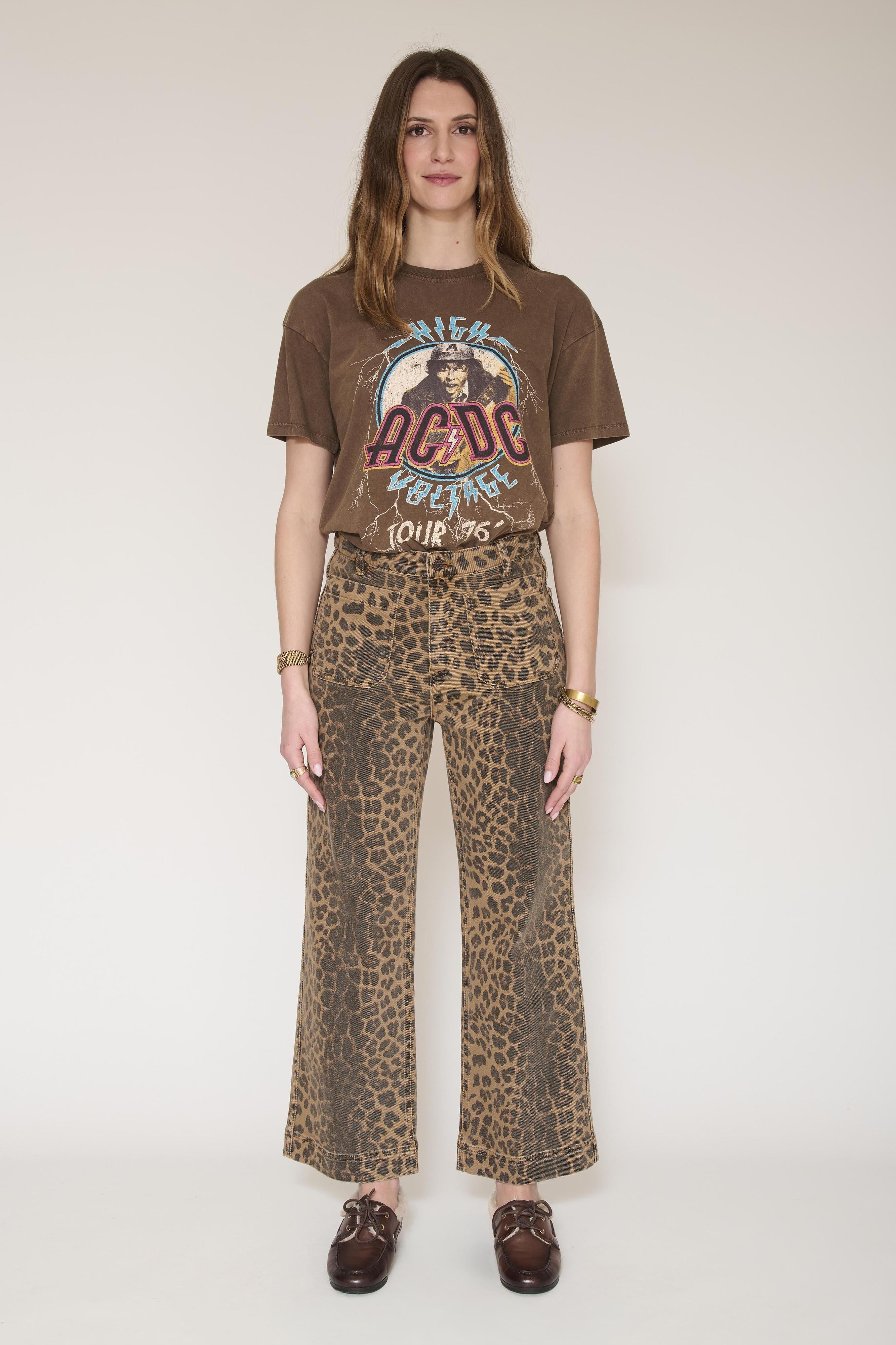 woman wears leopard print jeans with brown shoes and a brown printed tshirt by MKT against a white background