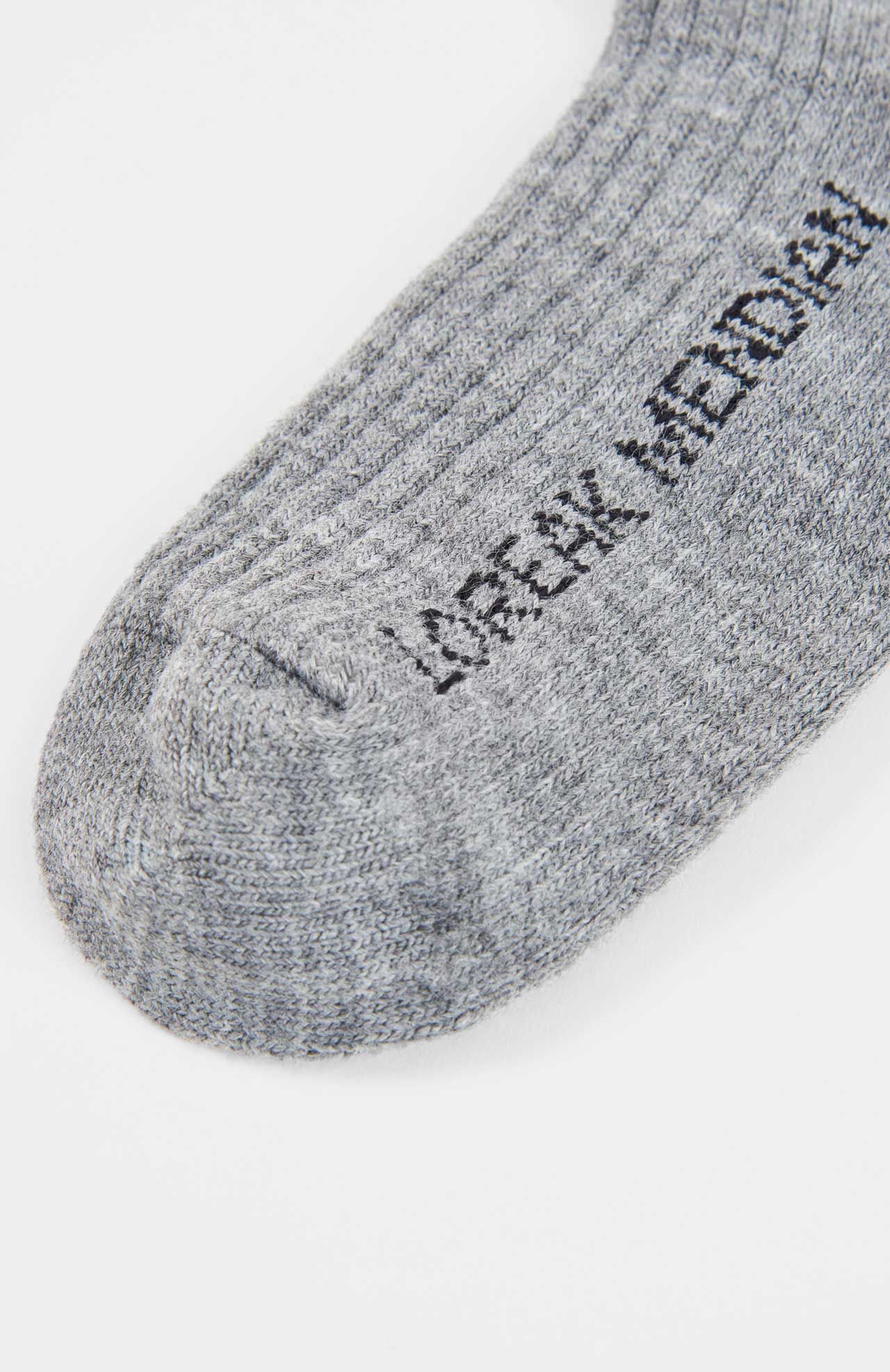 Close-up of the toe section of a grey Loreak Mendian Bioti Mid-Calf Sock, featuring partially visible black text on sustainable ribbed fabric.