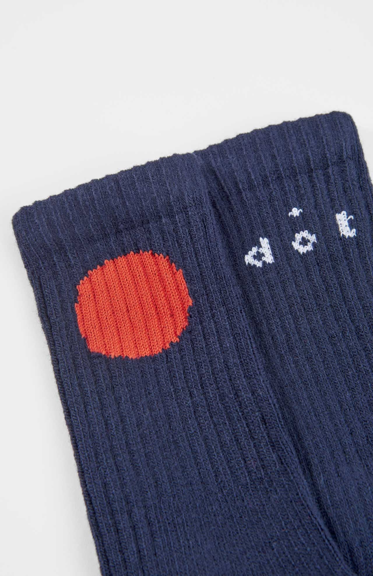 Close-up of Loreak Mendian Bioti Mid-Calf Socks in navy blue, featuring a large red circle and partial white text near the cuff; crafted sustainably with stylish ribbed detailing.