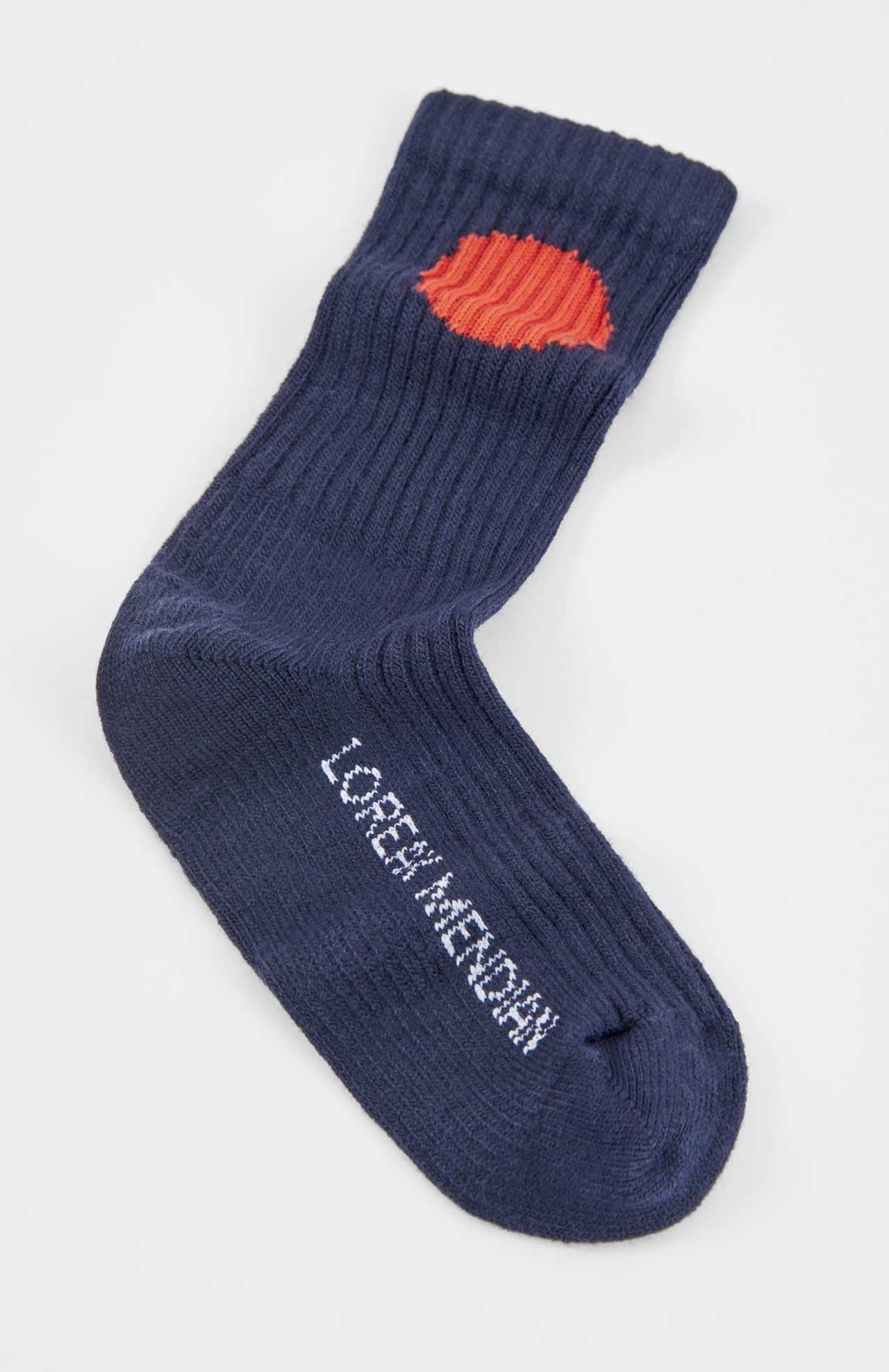 The Bioti Mid-Calf Socks by Loreak Mendian are navy blue, ribbed, with a red circle on the ankle and "LOREM MERDAH" in white along the side, reflecting the brand’s iconic style.