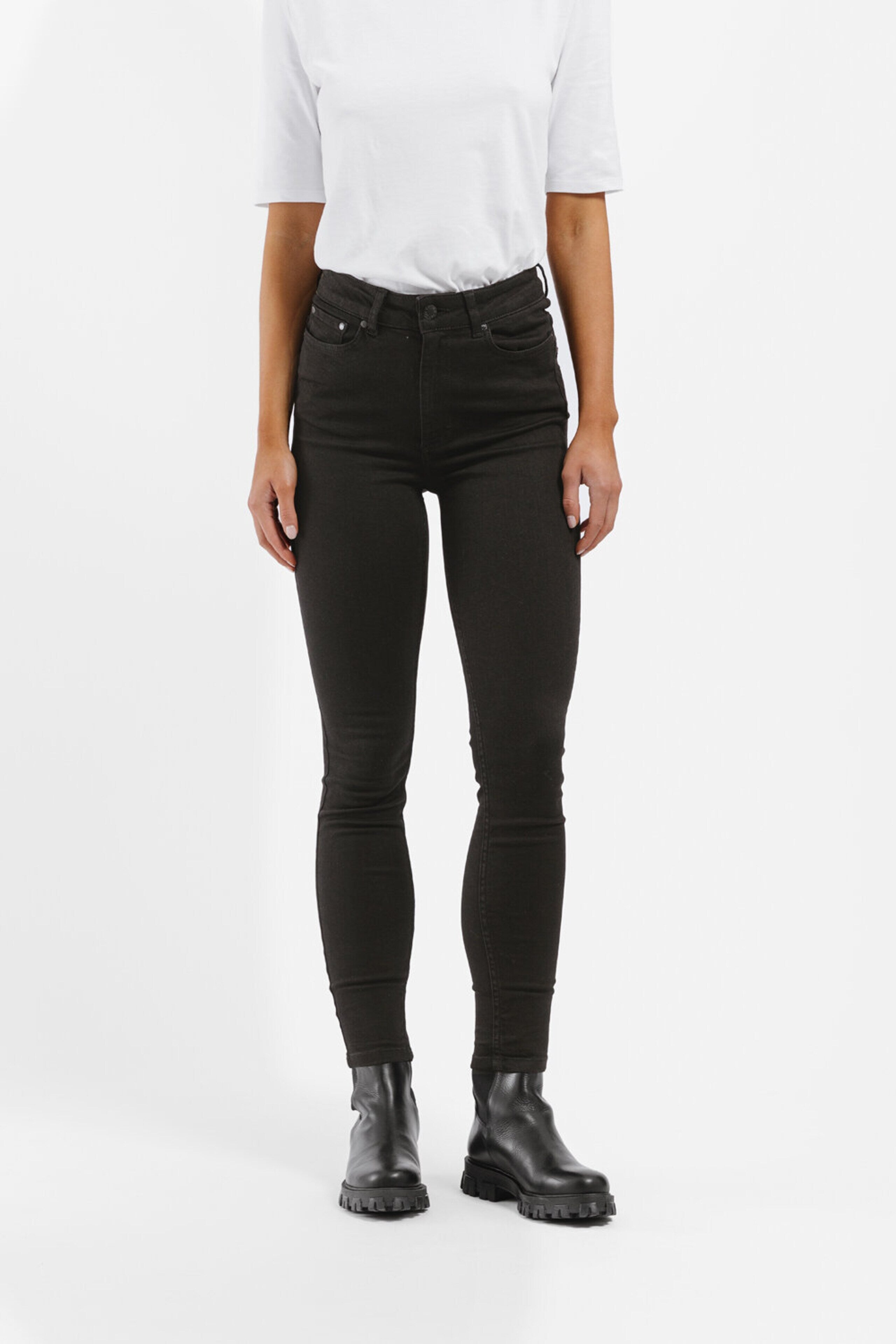 A woman wearing Julie High Waist Skinny Jeans - Black from Twist & Tango, which are super stretch black jeans with a high waist and an ankle length.