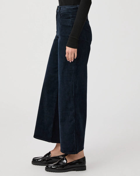 Side view of a person wearing Paige's Harper Ankle Wide Leg in Navy Corduroy, styled with a black long-sleeve top and black loafers.