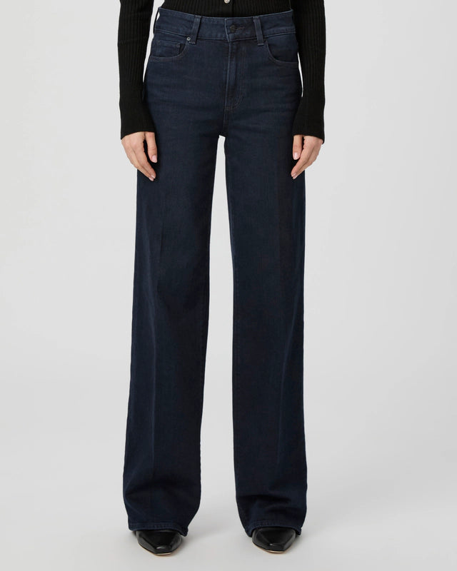 Someone wearing Paige’s Sasha Wide Leg - Duchess jeans with a black long-sleeve top, standing against a plain light background.