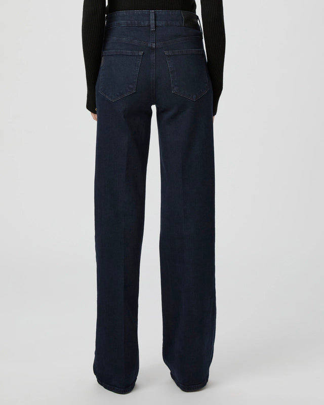 Photographed from the back against a plain background, a person wears Paige's Sasha Wide Leg - Duchess dark wash high-rise jeans with a black long-sleeve top.