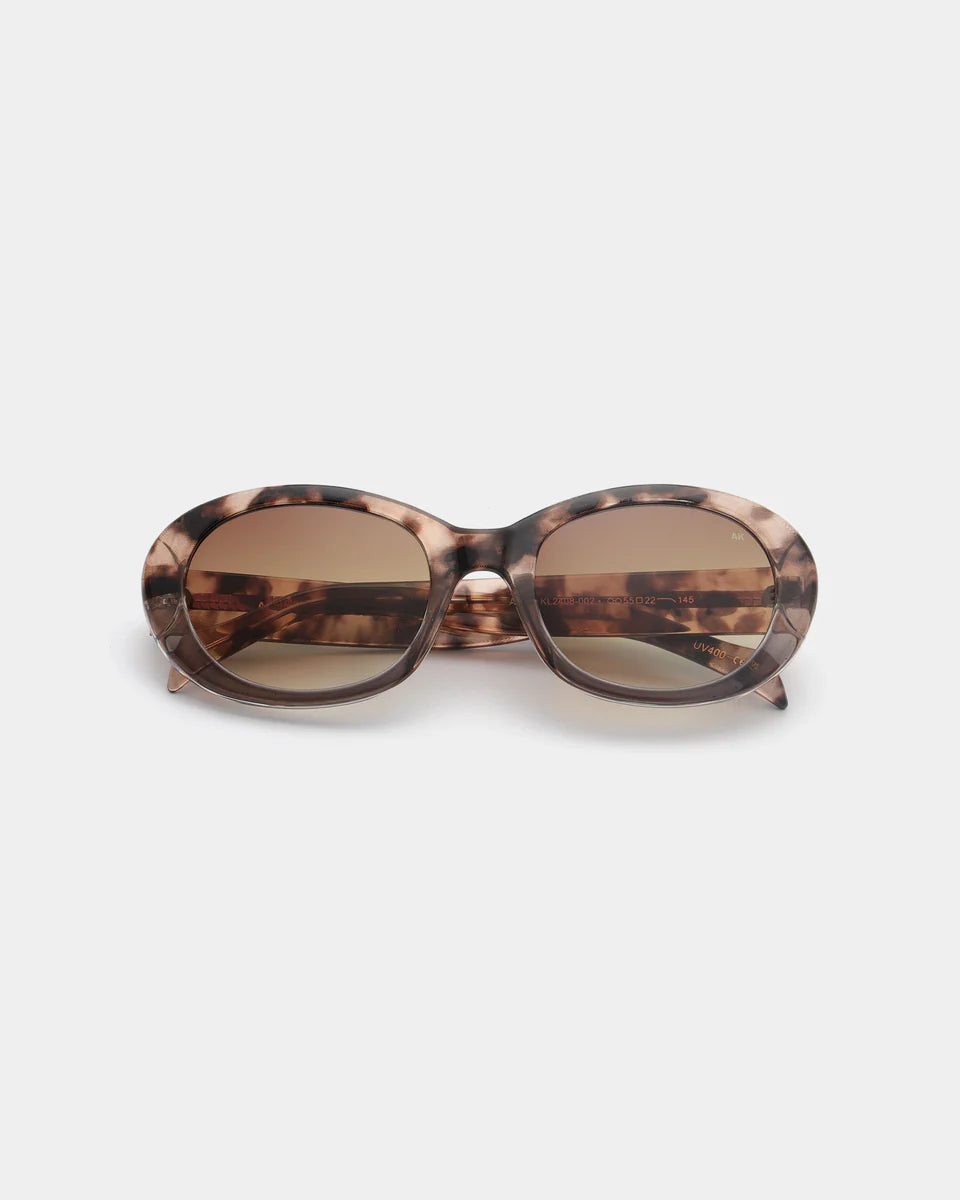The Anma Sunglasses - Coquina / Grey Transparent by A. Kjærbede feature an elegant oval design with grey transparent frames and UV 400 protected dark lenses, showcased against a plain white background.