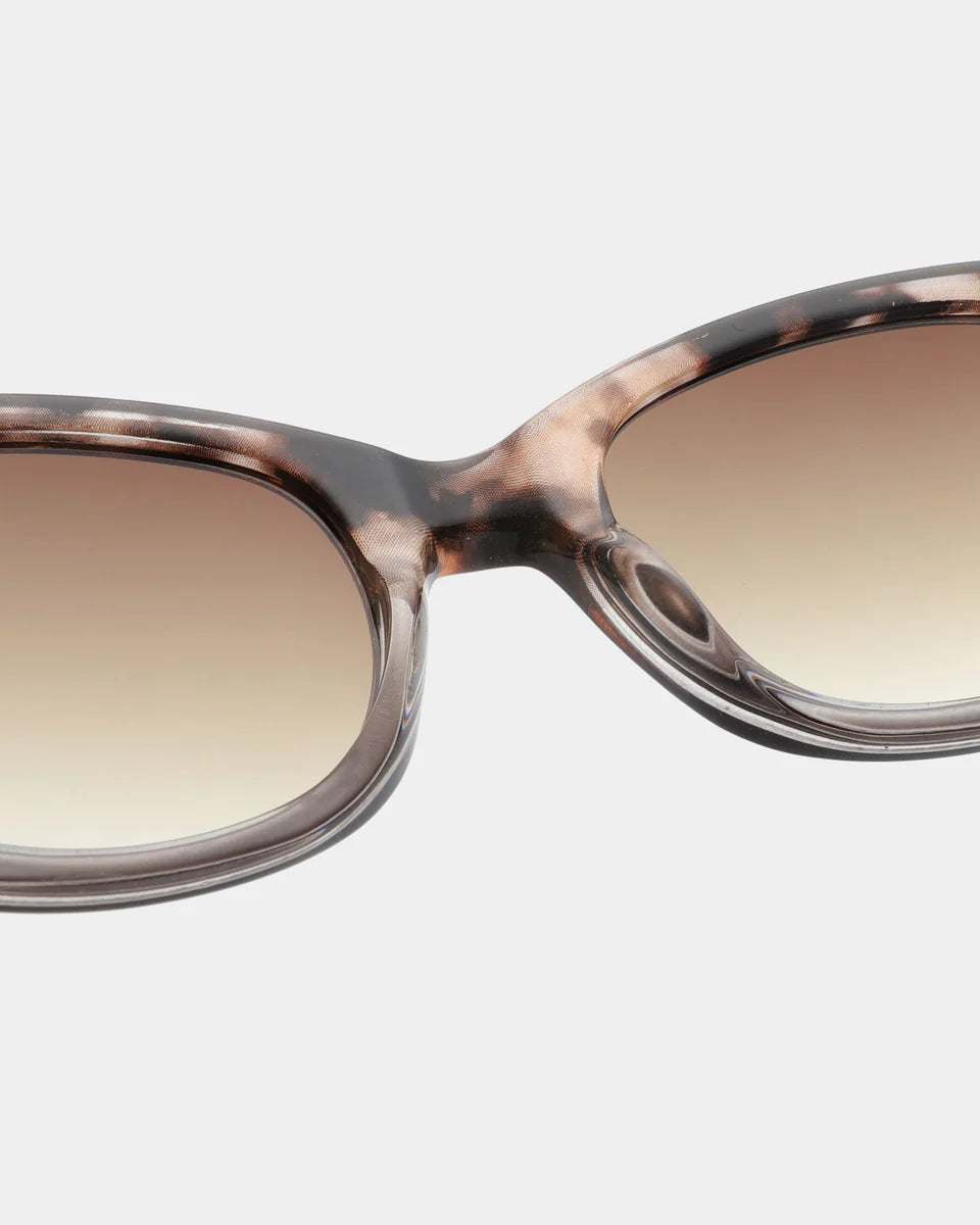 Close-up view of the Anma Sunglasses by A. Kjærbede, featuring a Coquina / Grey Transparent frame and gradient tinted lenses with UV 400 protection.