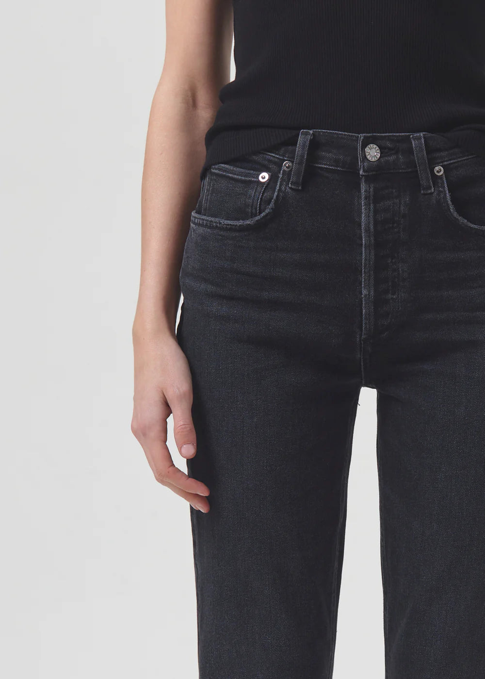 The high-rise back view of a woman wearing black AGOLDE Riley Straight Crop - Panoramic jeans with a slim straight leg cut.