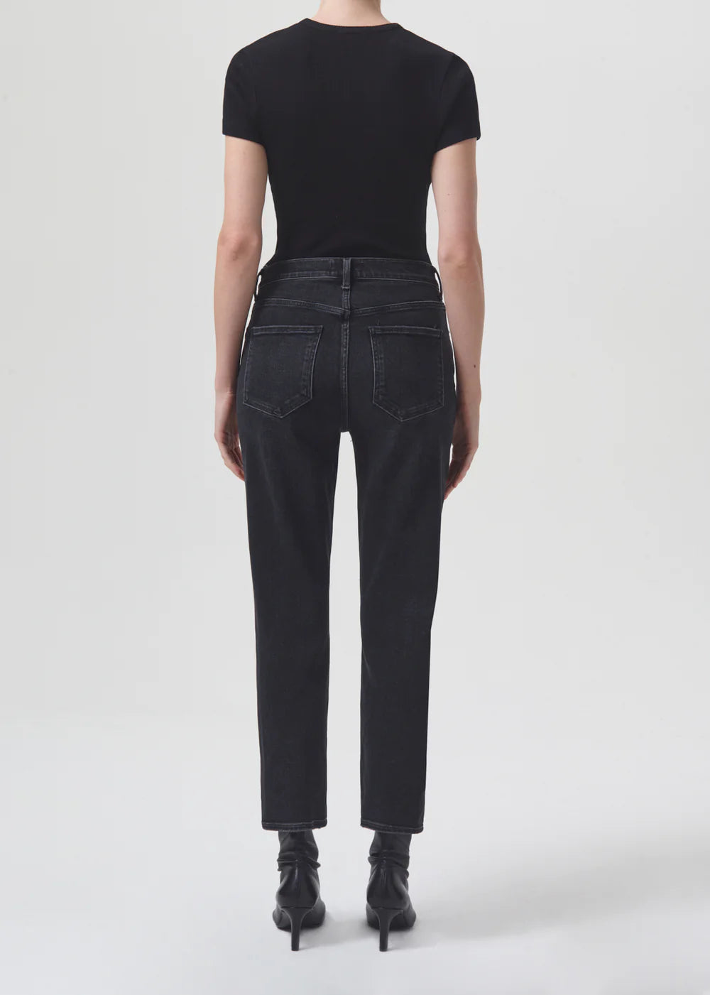 The back view of a woman wearing AGOLDE's Riley Straight Crop - Panoramic black jeans.