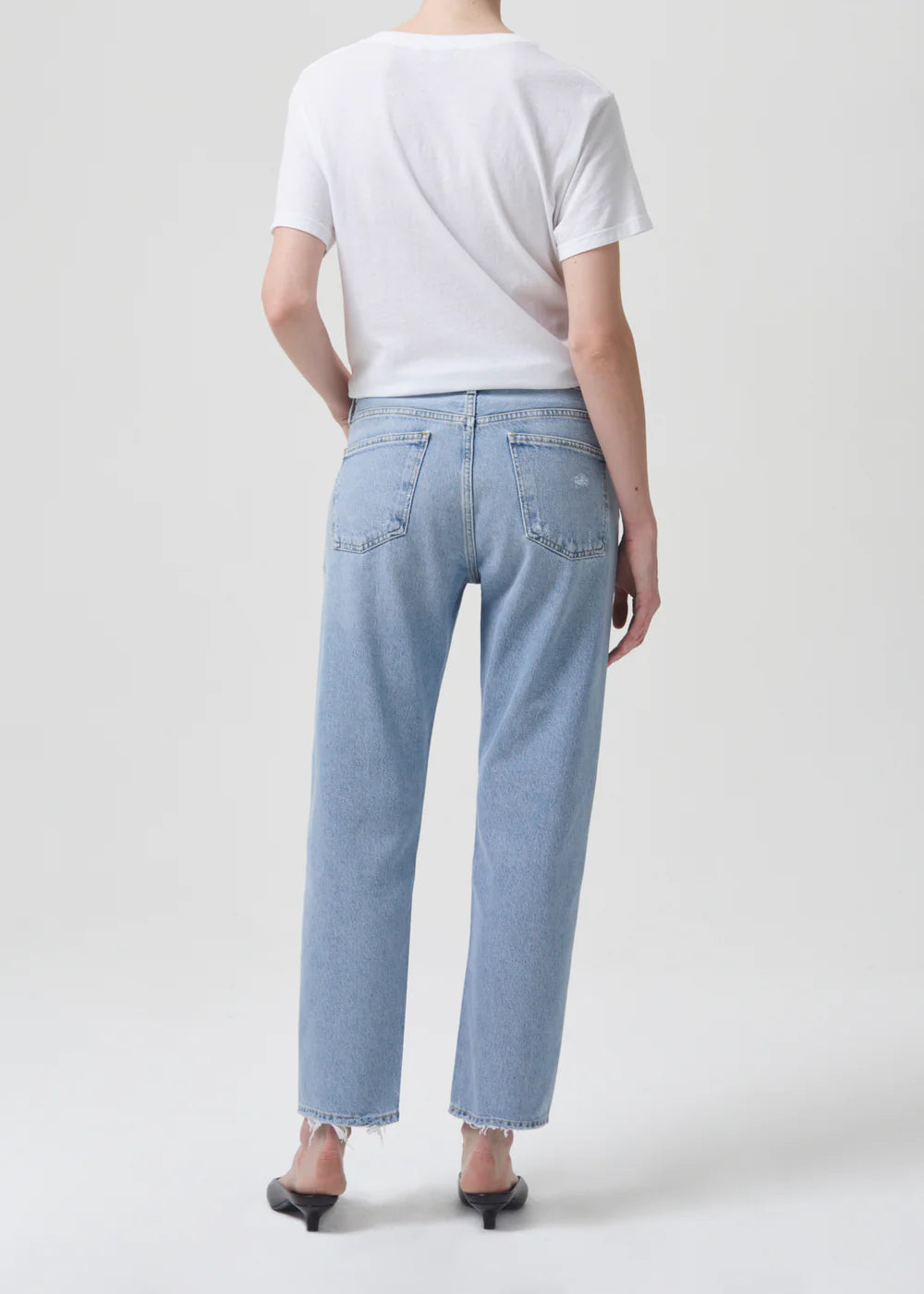 The back view of a woman wearing AGOLDE Parker jeans and a white t-shirt made of zero-stretch cotton.