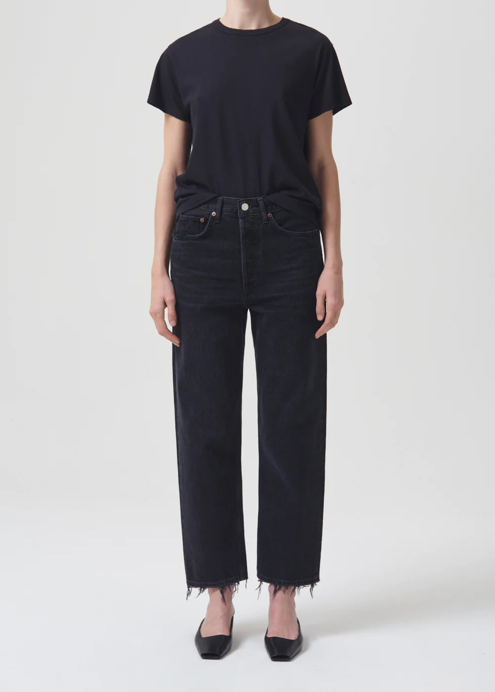 A woman wearing AGOLDE 90's Crop - Tar black jeans with a cropped inseam and a black t-shirt.