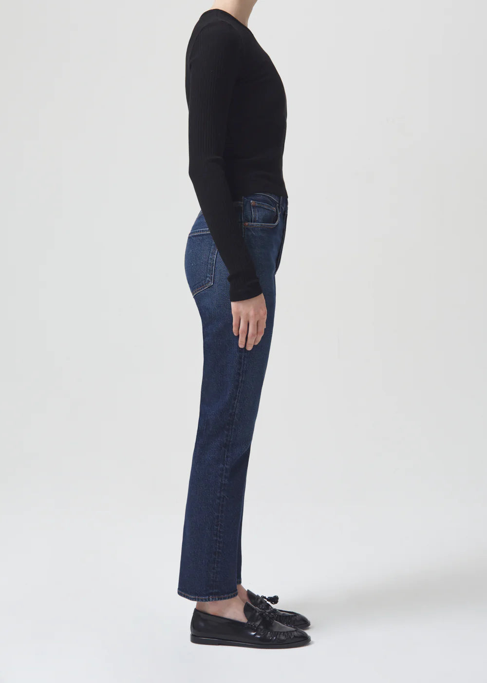 A woman wearing AGOLDE Riley Straight Long - Divided high-rise black jeans and a black sweater.