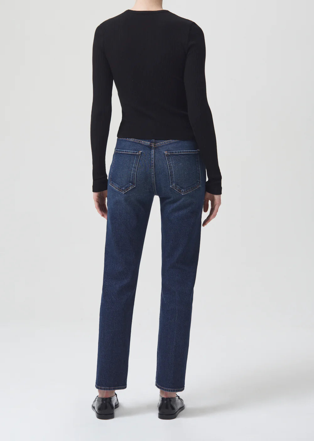 The back view of a woman wearing AGOLDE Riley Straight Long - Divided jeans, a black sweater.