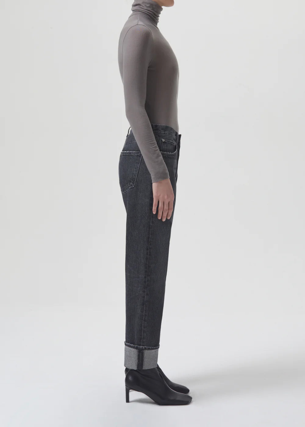 A woman wearing black AGOLDE Fran Low Slung Straight - Ditch jeans, made with AGOLDE's regenerative cotton, and a turtle neck top.