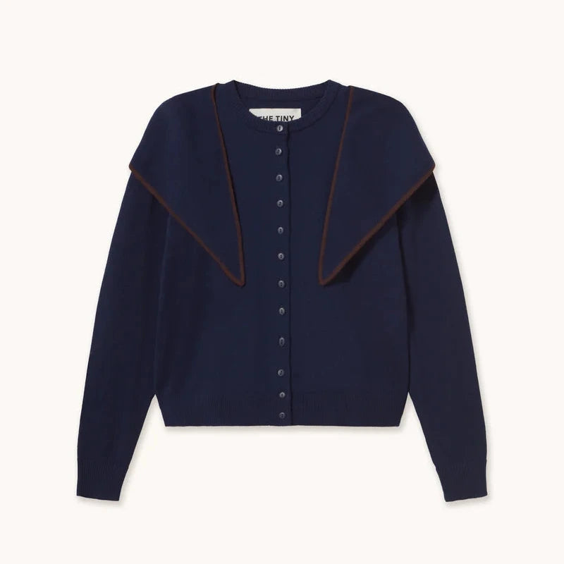 A navy blue cropped cardigan sweater with a wide, draped collar and a button-up front, shown flat on a light cream background.